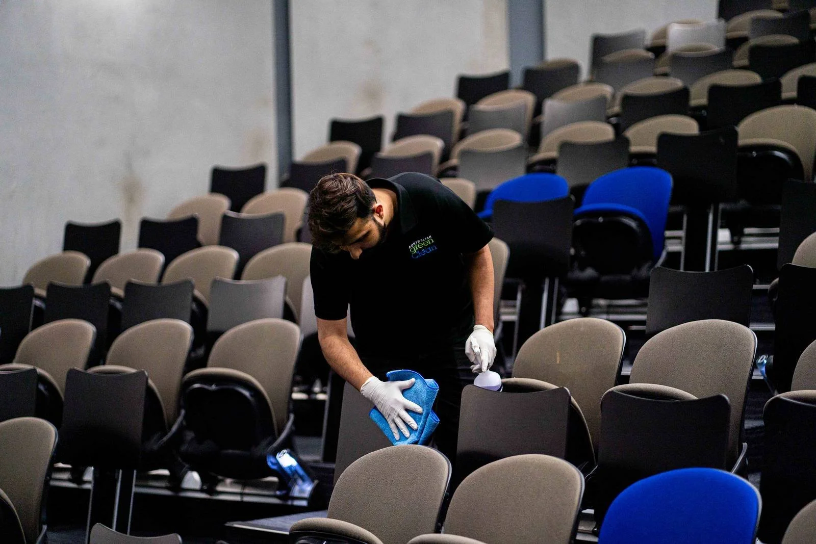 Person cleaning seats in an empty auditorium or conference hall.