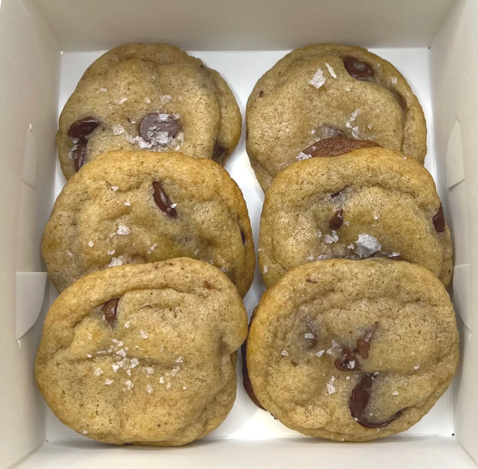 A box of six chocolate chip cookies sprinkled with sea salt.