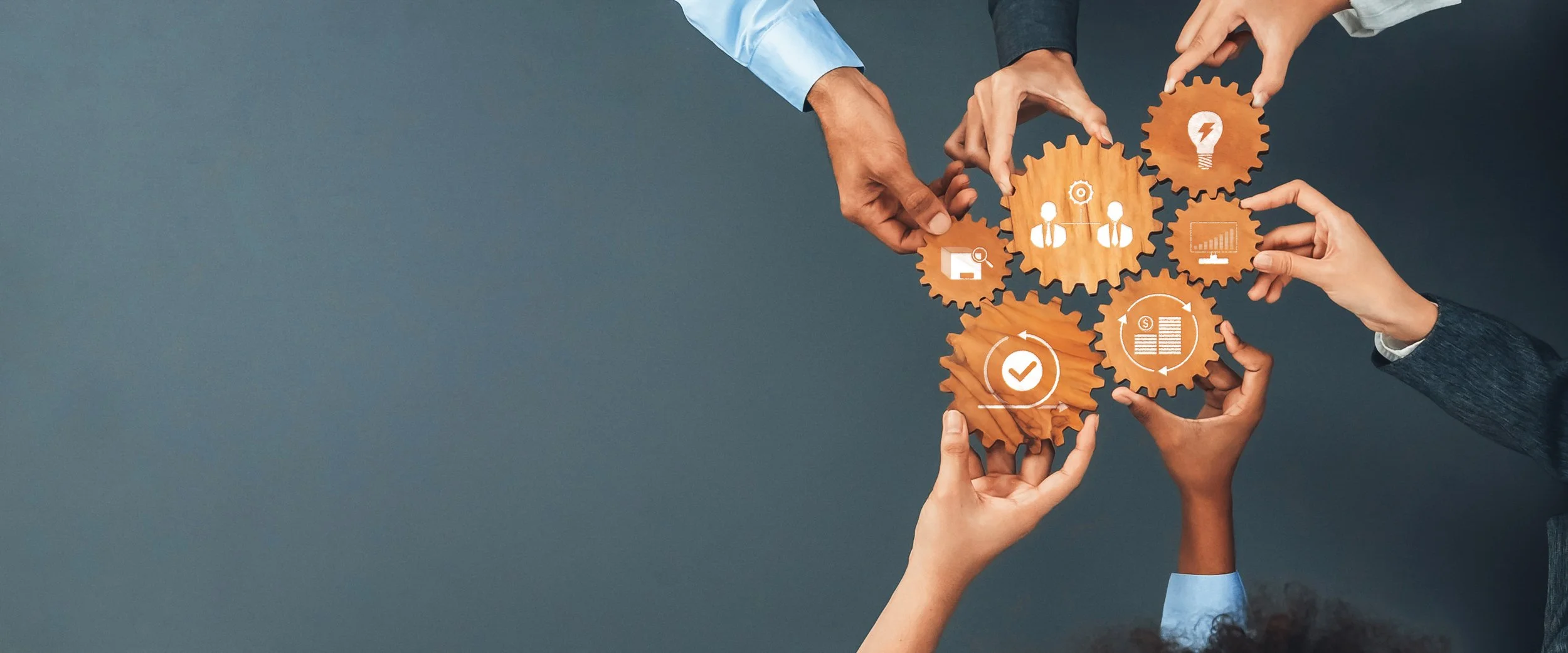 Multiple hands connecting wooden gears with icons representing business and technology concepts.