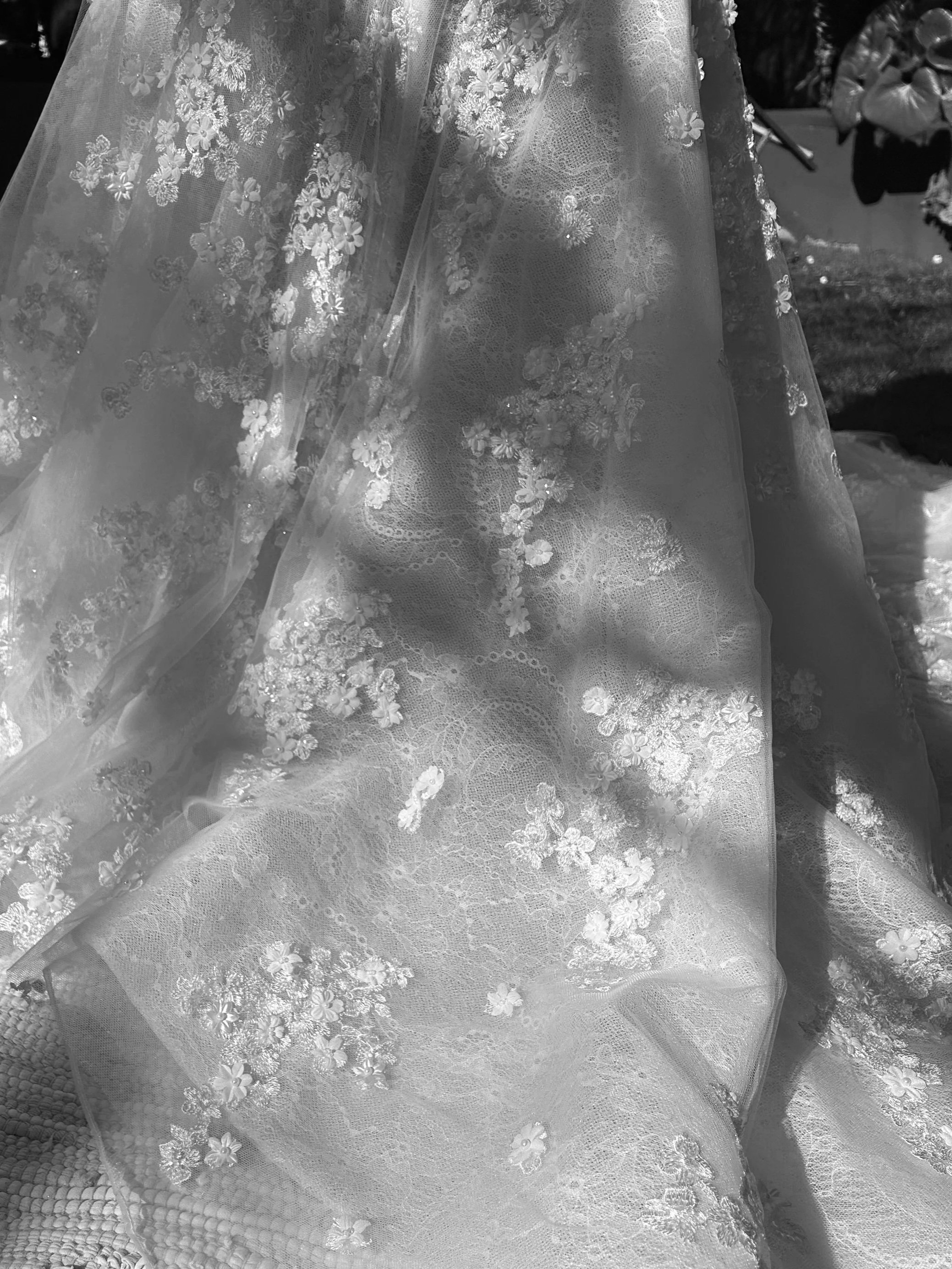 Close-up of a wedding dress with detailed floral embroidery and lace fabric.