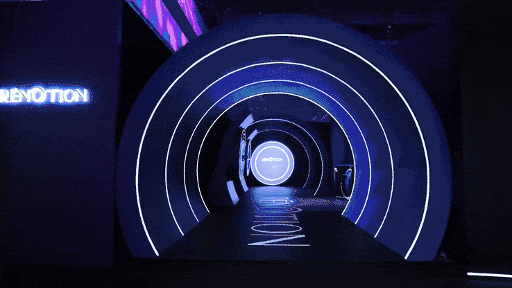A futuristic tunnel with concentric neon white circles and blue lighting, leading to a circular illuminated sign that reads 'Renotion.'