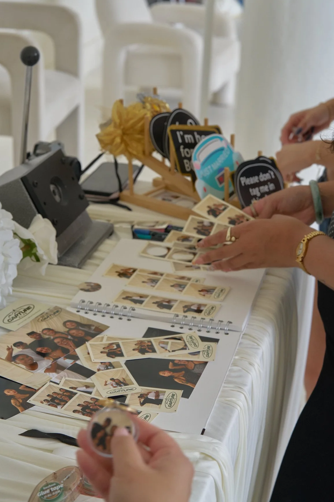 People are organizing and handling photo booth pictures and props on a table at a celebration or event.