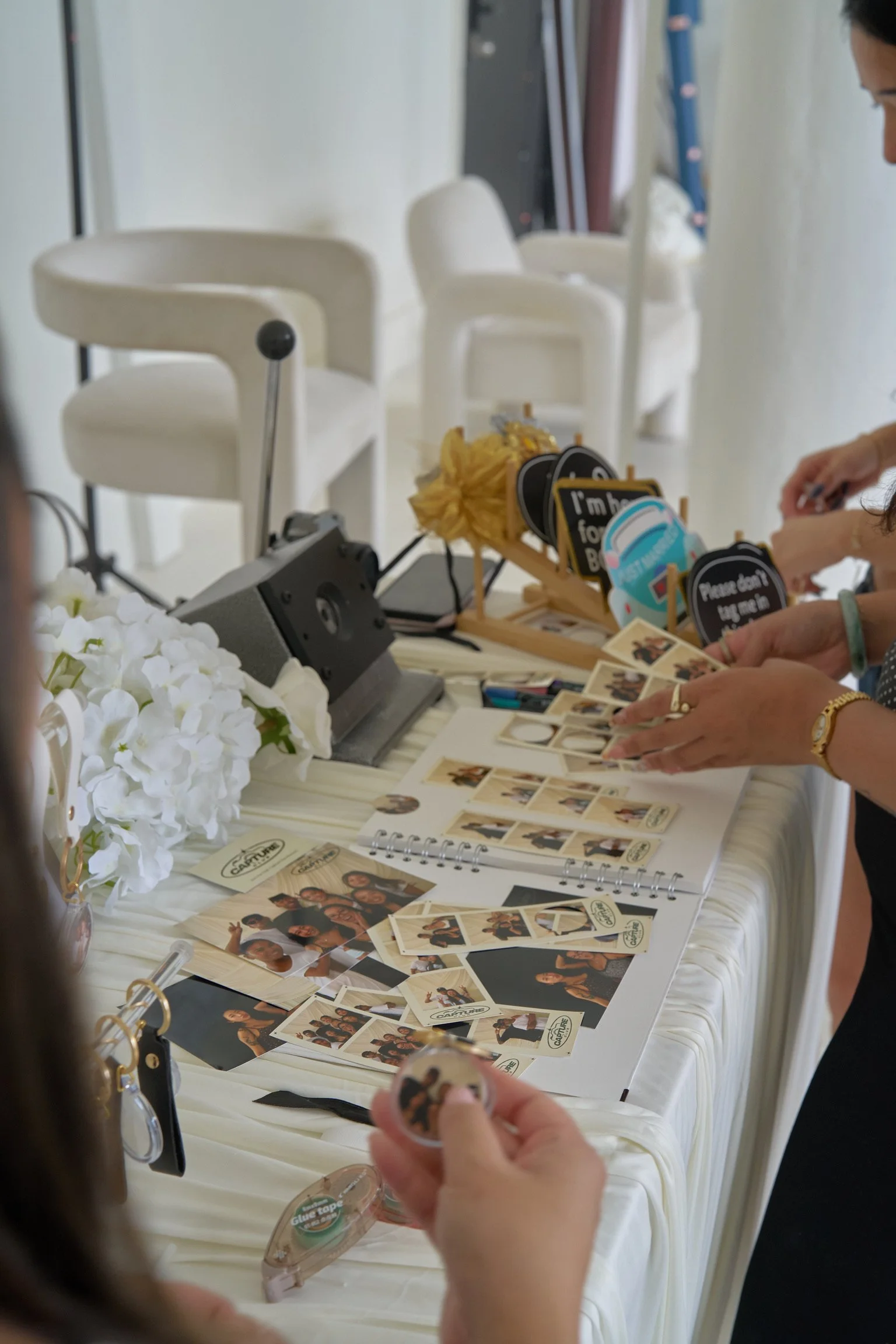 Guests at a photo booth with props and printed photographs during a celebration or event.