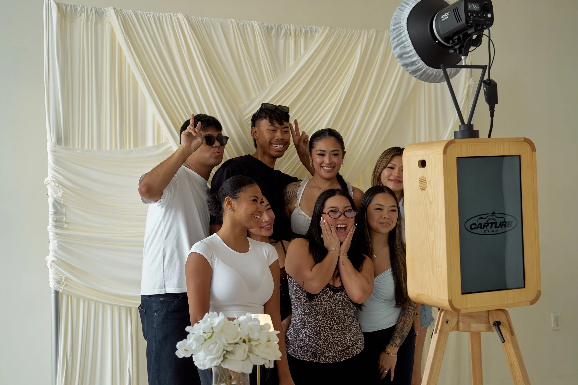 Group of people taking a photo with a photo booth at a celebration event.