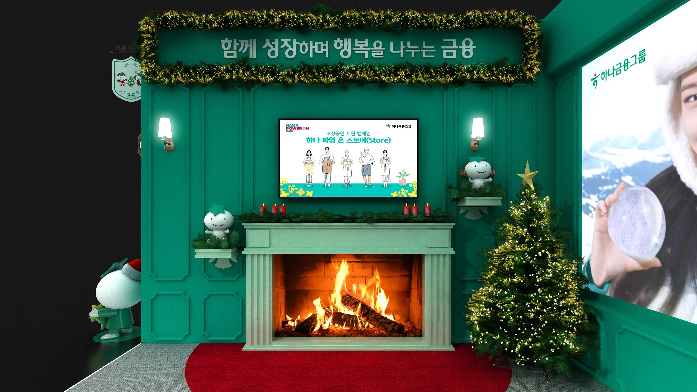 초록색 벽에 걸린 크리스마스 장식과 벽난로가 있는 공간, 벽에는 '함께 성장하며 행복을 나누는 금융'이라는 문구가 적혀 있으며, 벽 난로 위에는 그림이 그려진 디지털 화면이 있고, 양쪽에 벽등이 달려 있으며, 크리스마스트리와 귀여운 캐릭터들이 배치되어 있어 크리스마스 분위기를 연출하고 있음.