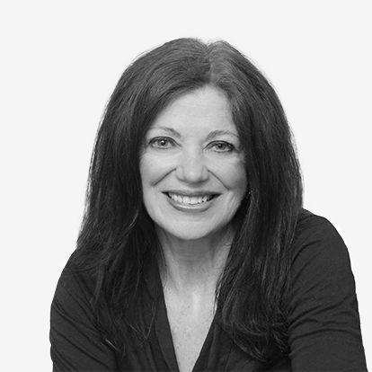 A black and white portrait of a smiling woman with shoulder-length dark hair, wearing a black top.