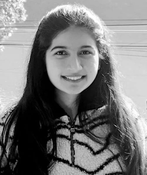 Young woman with long dark hair smiling outdoors in black and white