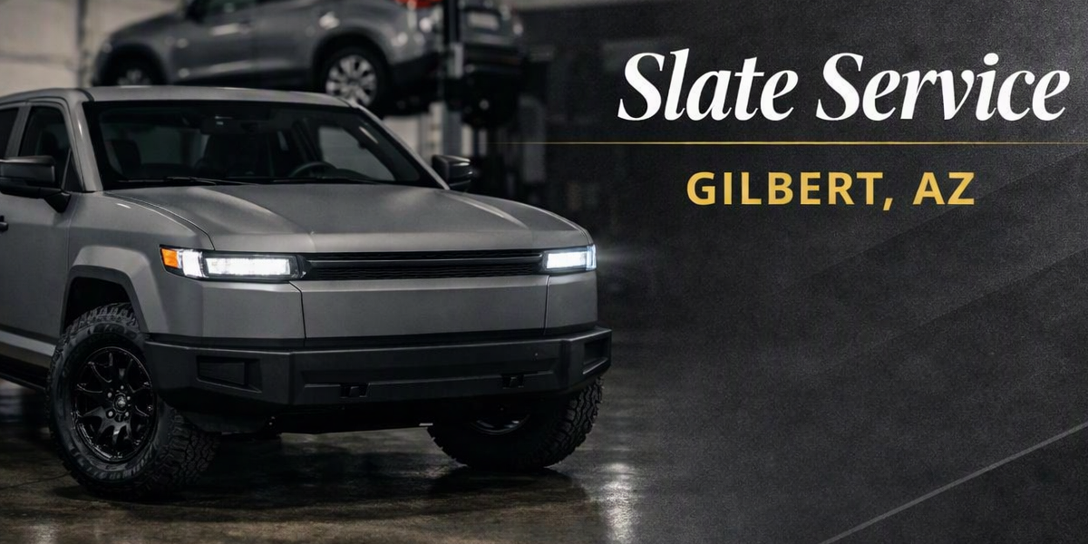 Gray SUV in a garage with a stack of cars in the background, and text that reads 'Slate Service Gilbert, AZ'.