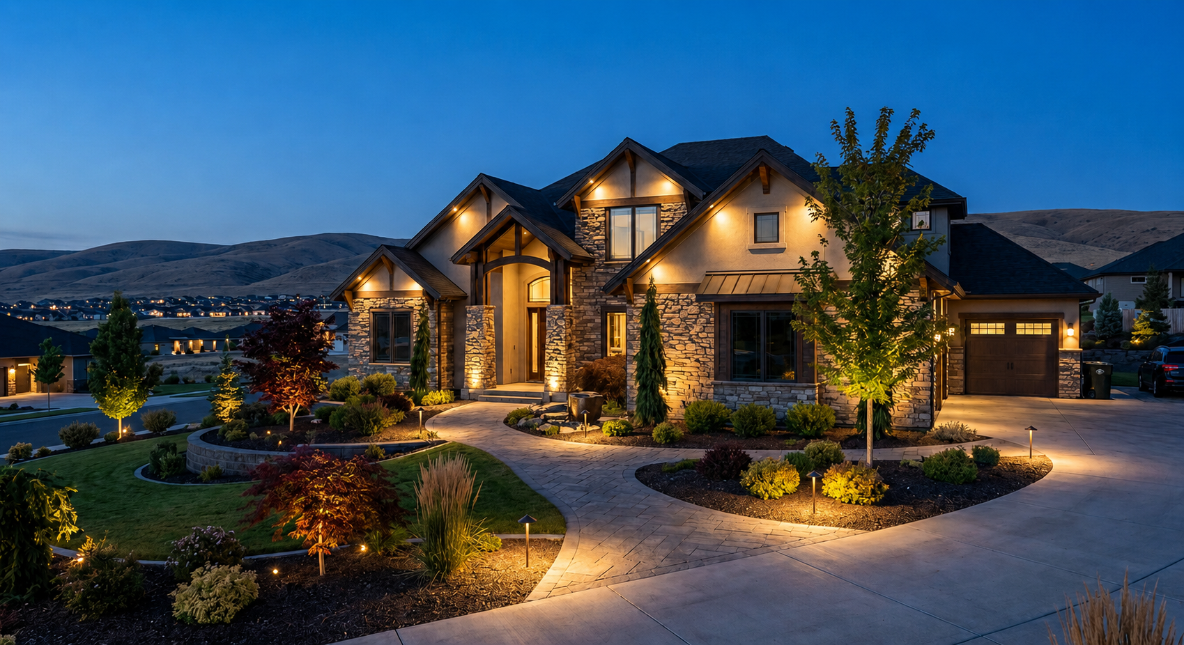 Luxury house with stone facade, landscaped yard with pathway, trees, and exterior lighting at dusk