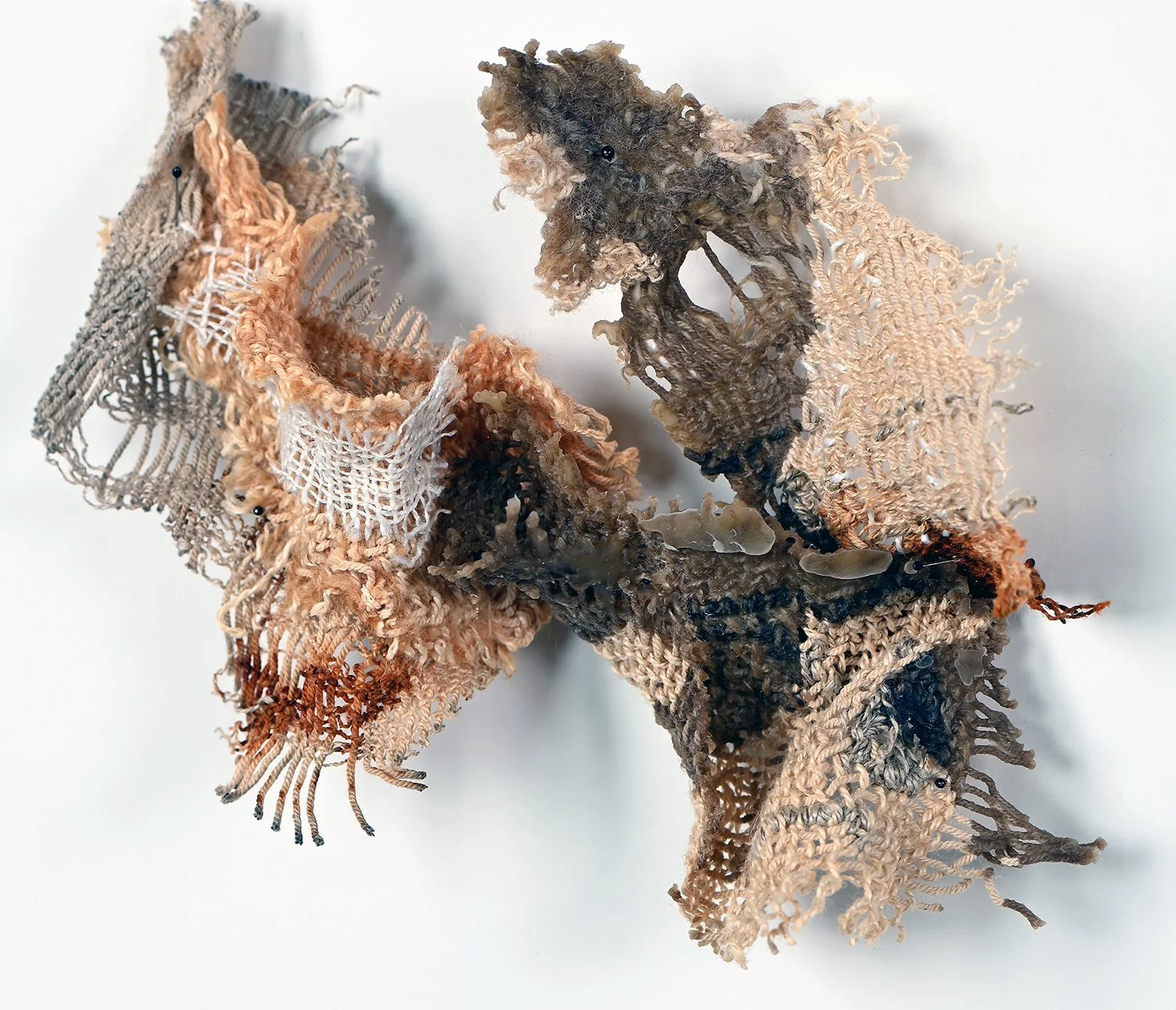 Art installation made of shredded fabric and mesh attached to a wall.