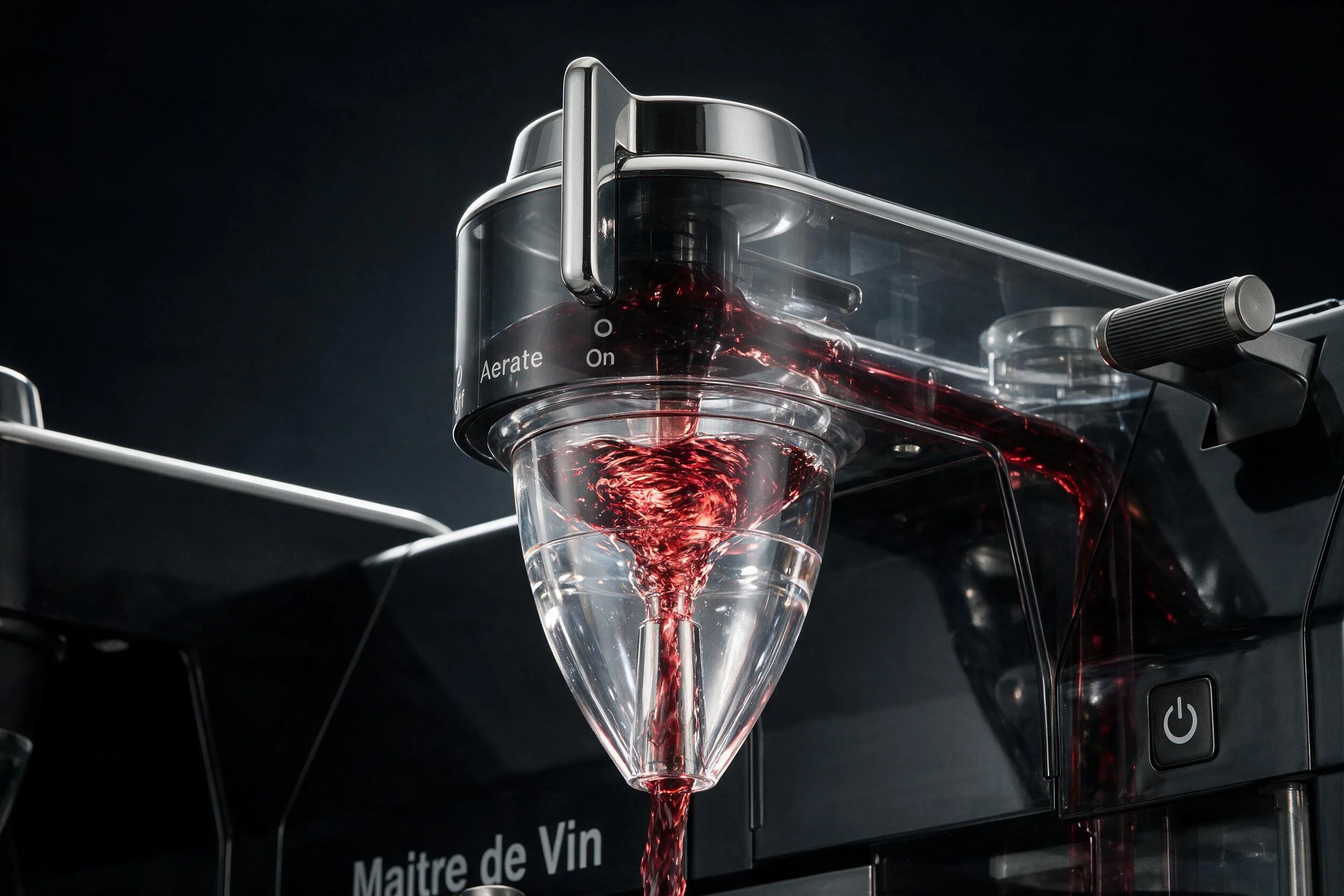 A close-up of a modern wine aerator with a vacuum wine pump attached, pouring red wine into a glass.