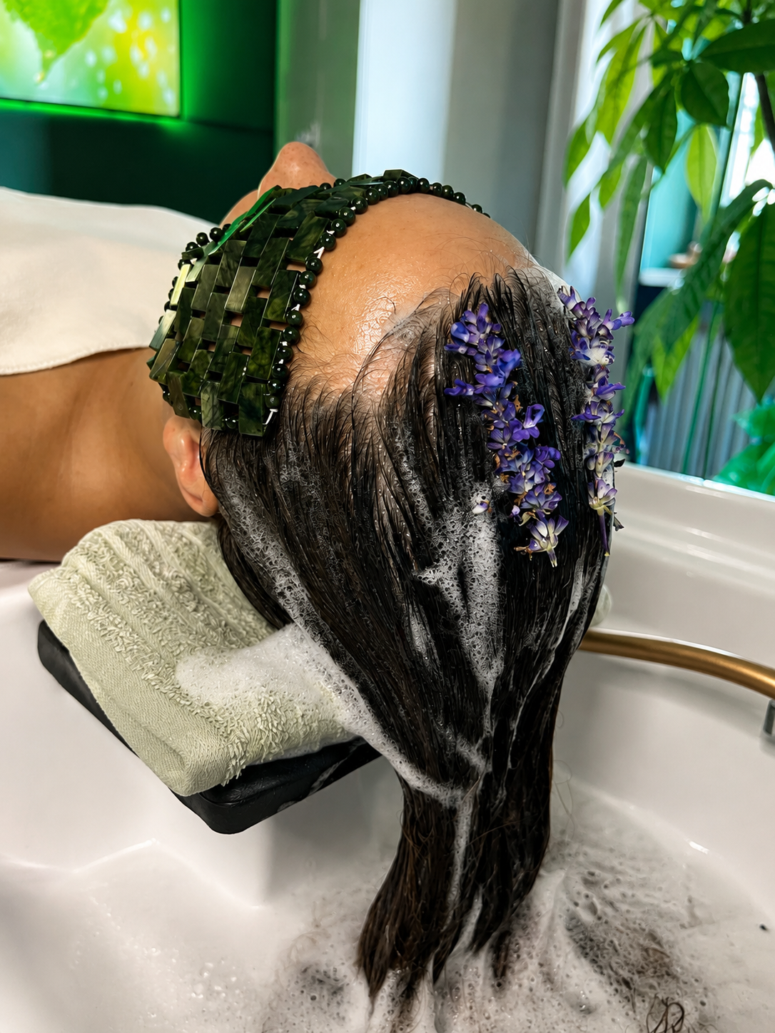 Frau bei einer Haarwäsche, mit Blumen im Haar, in einem Spa.