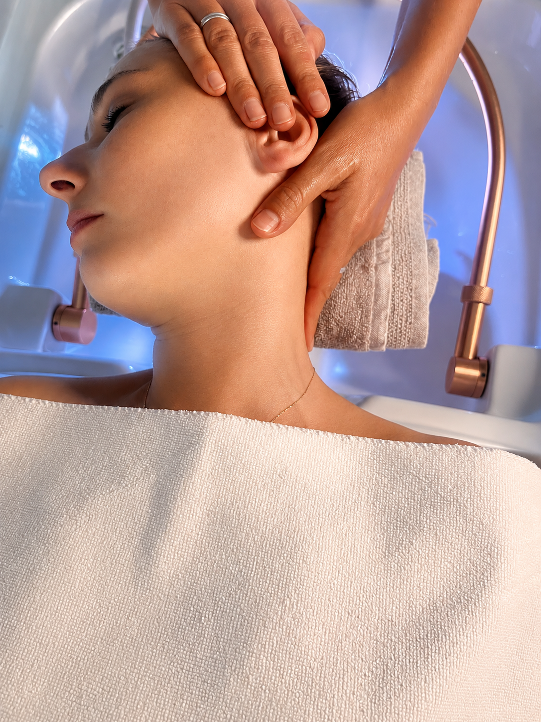 Ein Mensch erhält eine Gesichtsmassage in einem Spa oder einer Therapiestation, liegend mit entspanntem Gesicht und geschlossenem Auge.