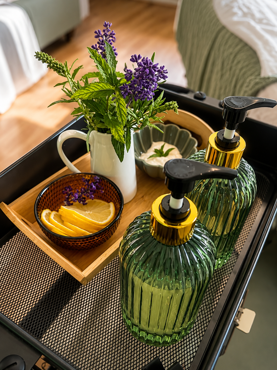Vase mit Lavendel und andere Pflanzen, zwei grüne Pumpflaschen, eine Schale mit Zitronenscheiben, Strauß mit Zitronenstücken und kleines Gefäß mit Creme oder Joghurt auf einem Tablett