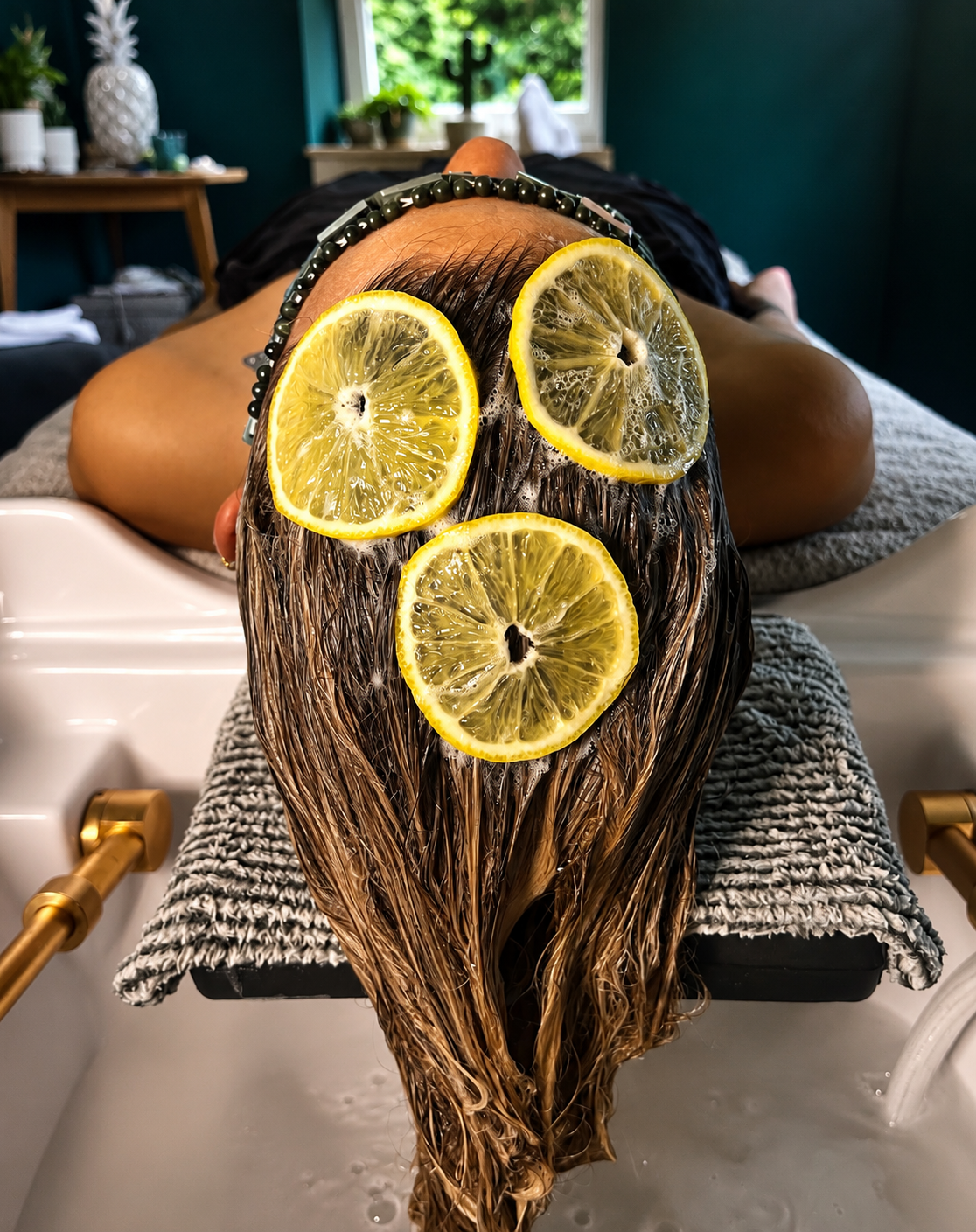 Eine Person erhält eine Haarpflege mit Zitronenscheiben auf dem Haar in einem Spa.