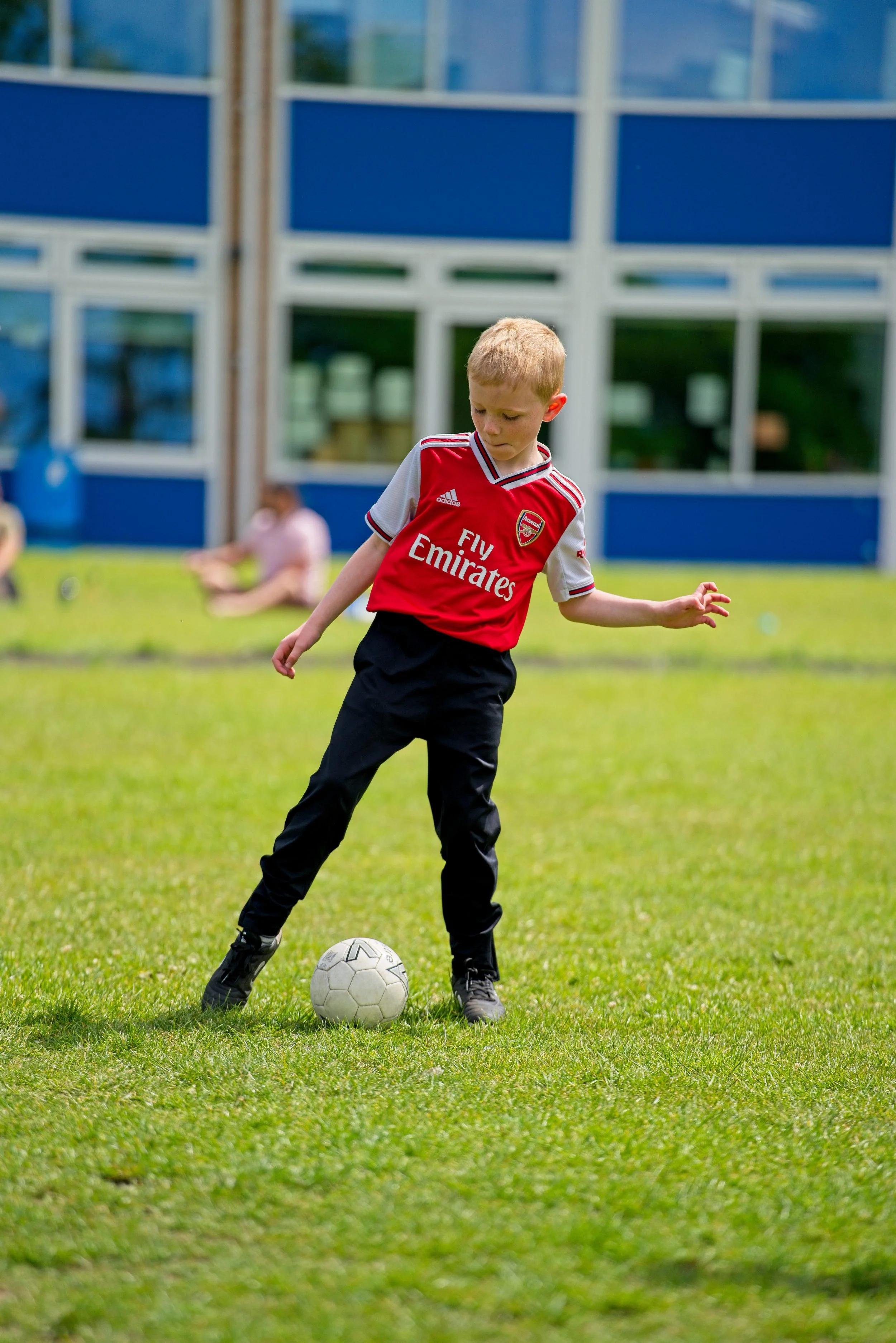 Student playing football wearing arsenal shirt at after school club at Warwick Primary School