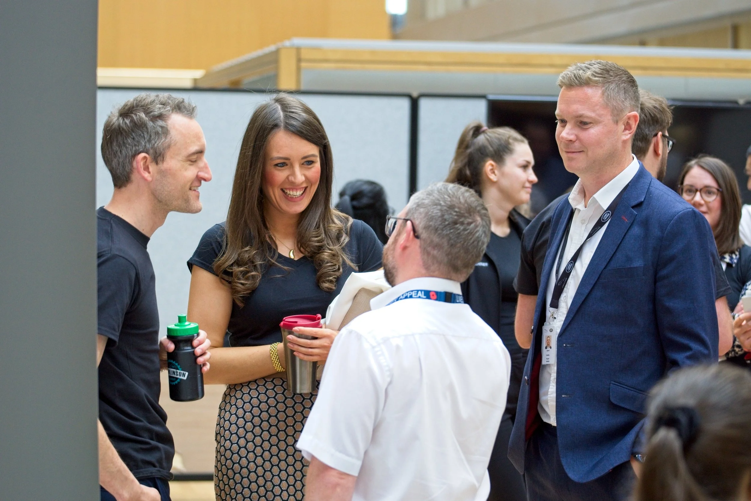 Group of professionals engaged in conversation at a conference or networking event, indoors with modern decor. Event Photography by photographer based in Southam, Warwickshire.
