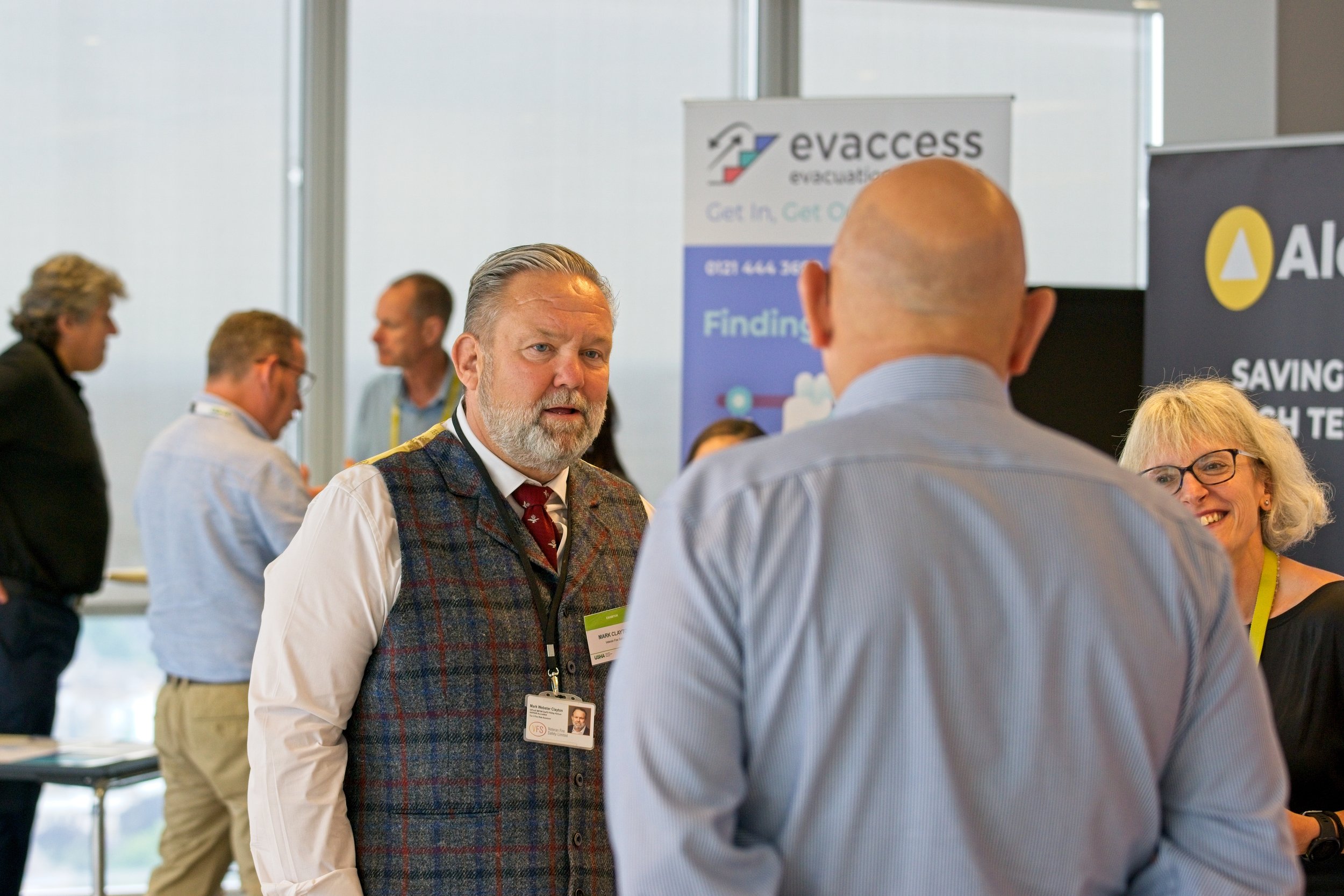 Group of professionals networking at a conference, engaging in conversation near informational booths. Event Photography by photographer based in Southam, Warwickshire.
