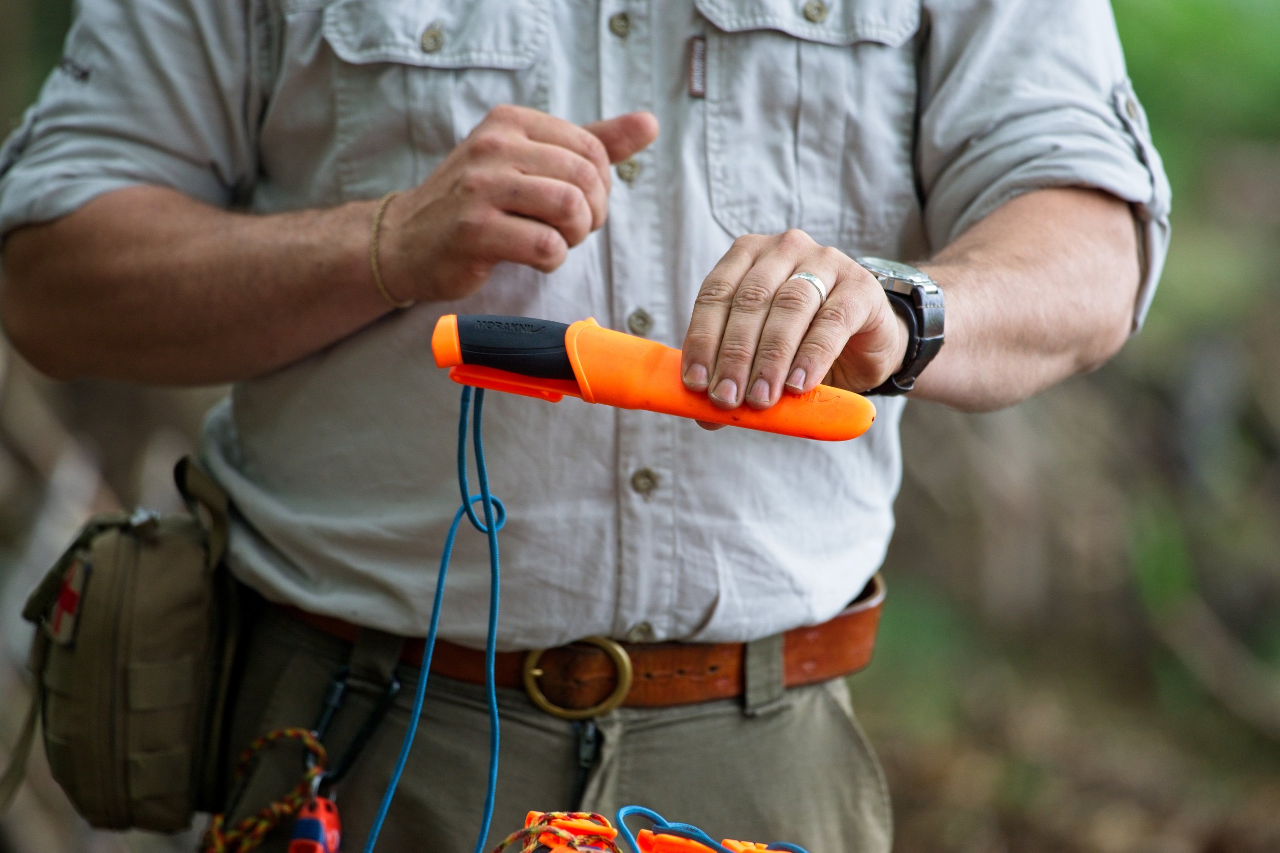 Person holding and inspecting a bright orange rescue whistle outdoors. Event Photography by photographer based in Southam, Warwickshire.