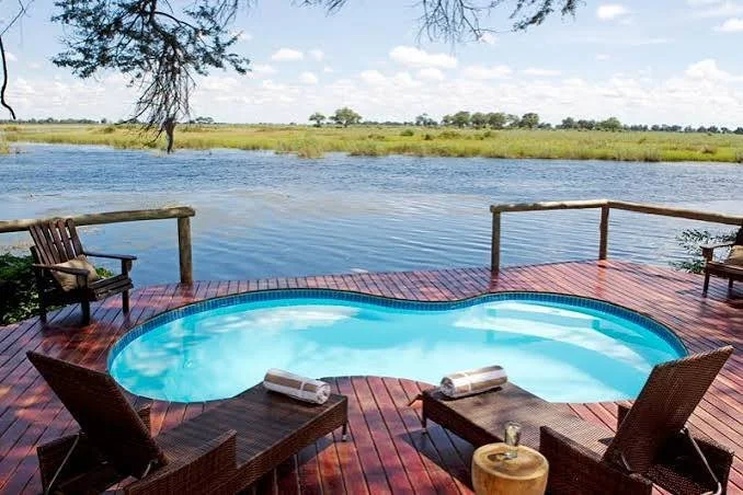 A private outdoor pool on a wooden deck overlooking a river with marshland and trees in the distance.