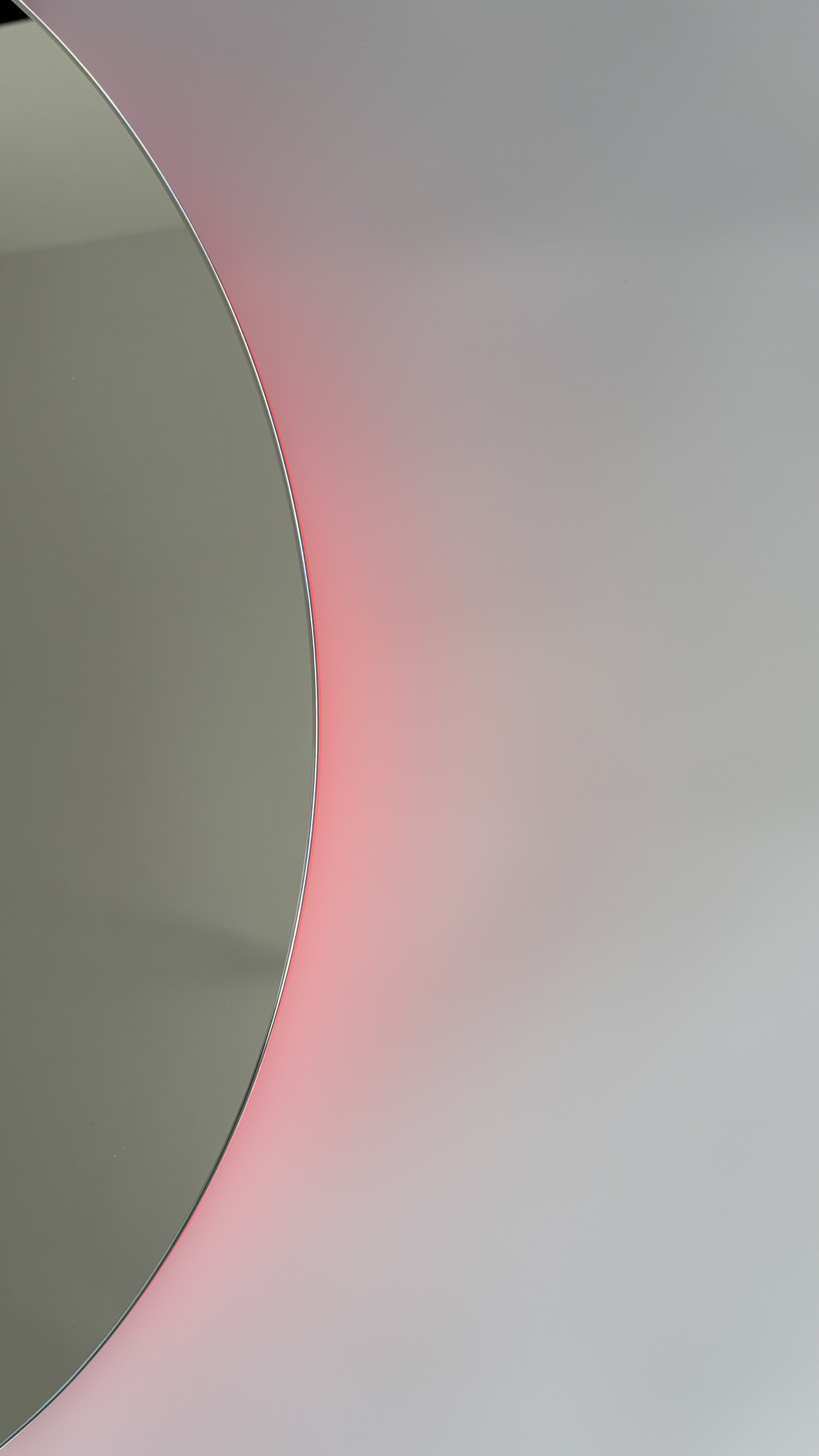 Dettaglio di un oggetto tecnologico con superfici lucide e tonalità di grigio e rosa, con un bordo sottile in metallo.