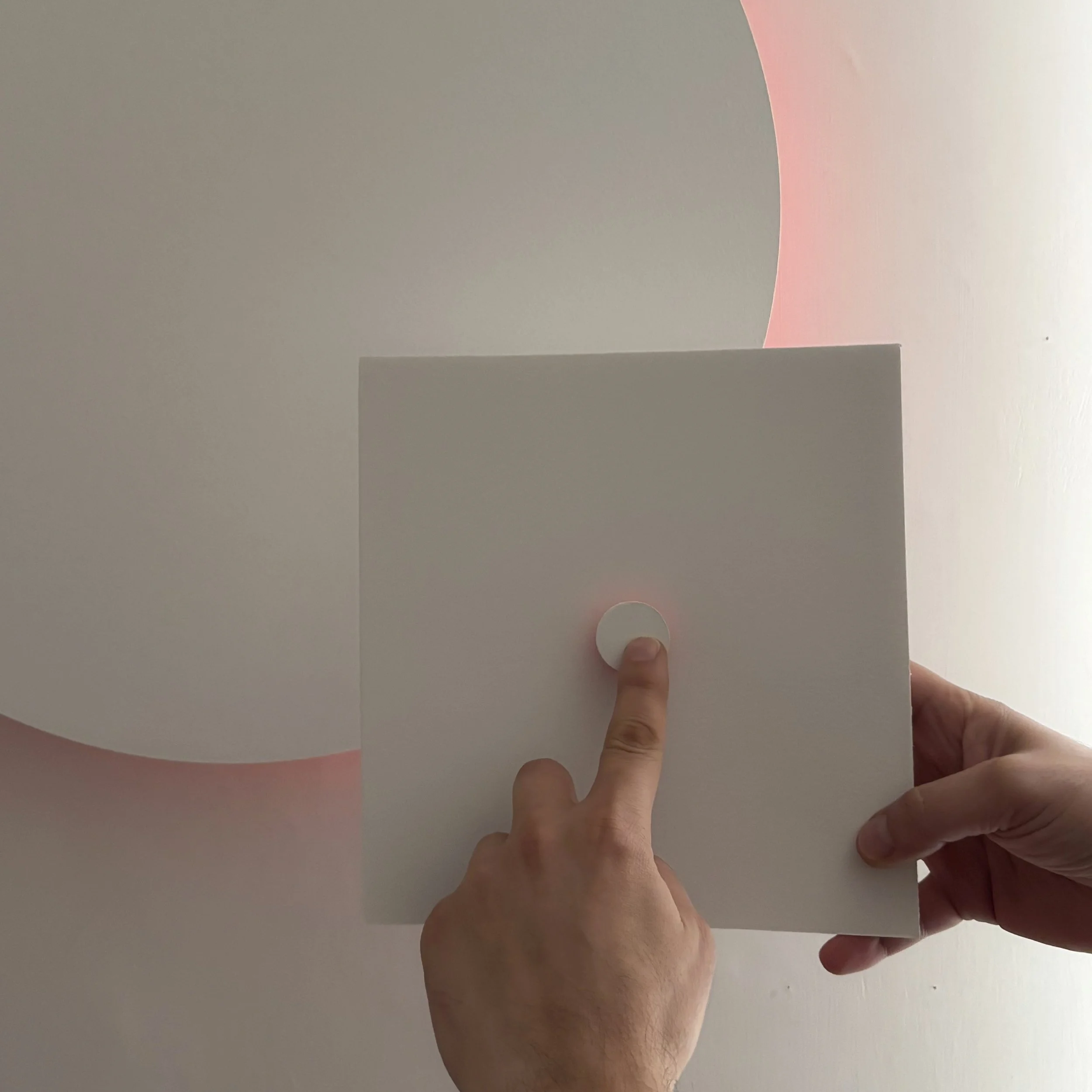 Una persona tiene un foglio di carta bianco e lo tiene davanti al suo viso, mentre con il dito indica il centro del foglio.