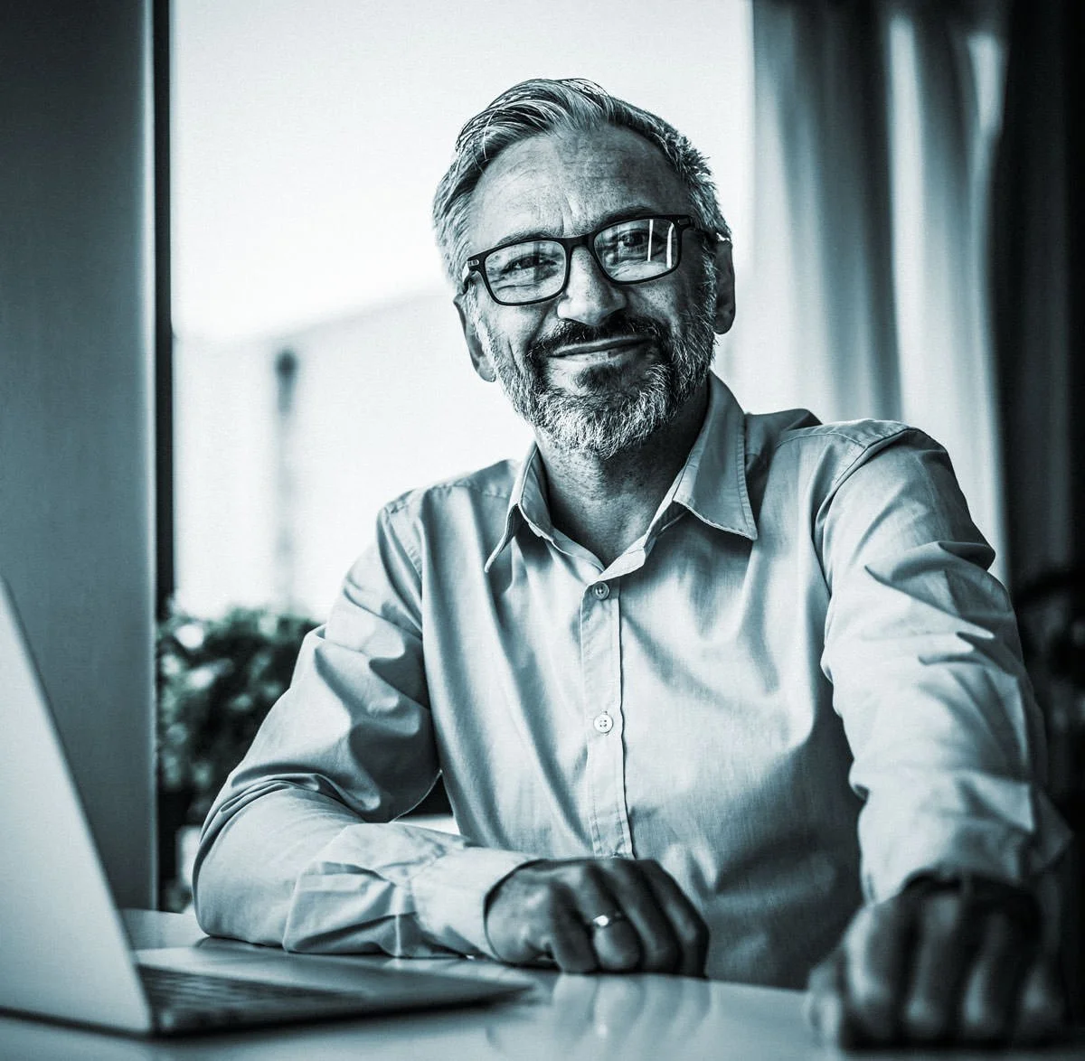 Mitarbeiter am Computer lächelt in Kamera