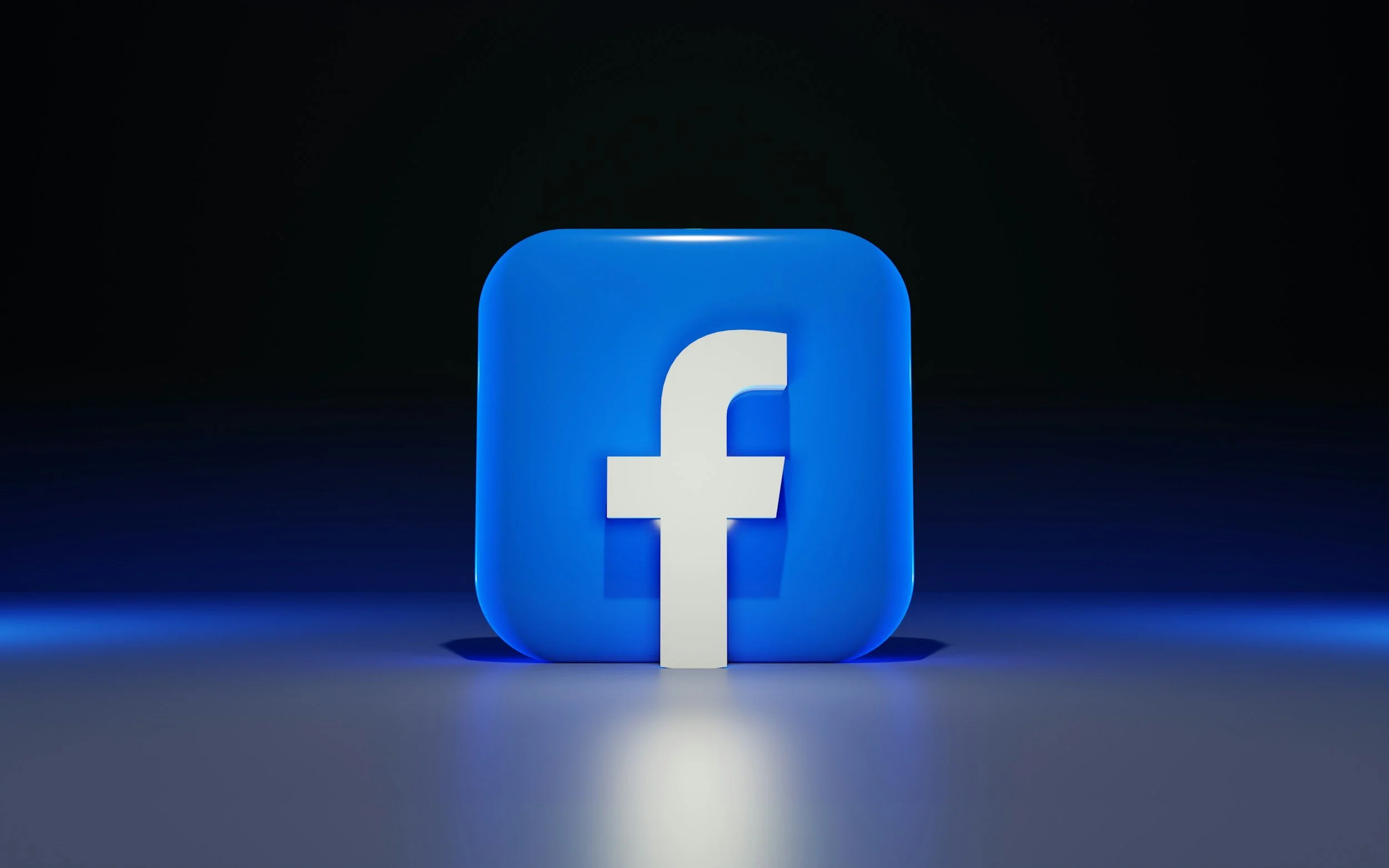Facebook logo illuminated in blue on a dark background.