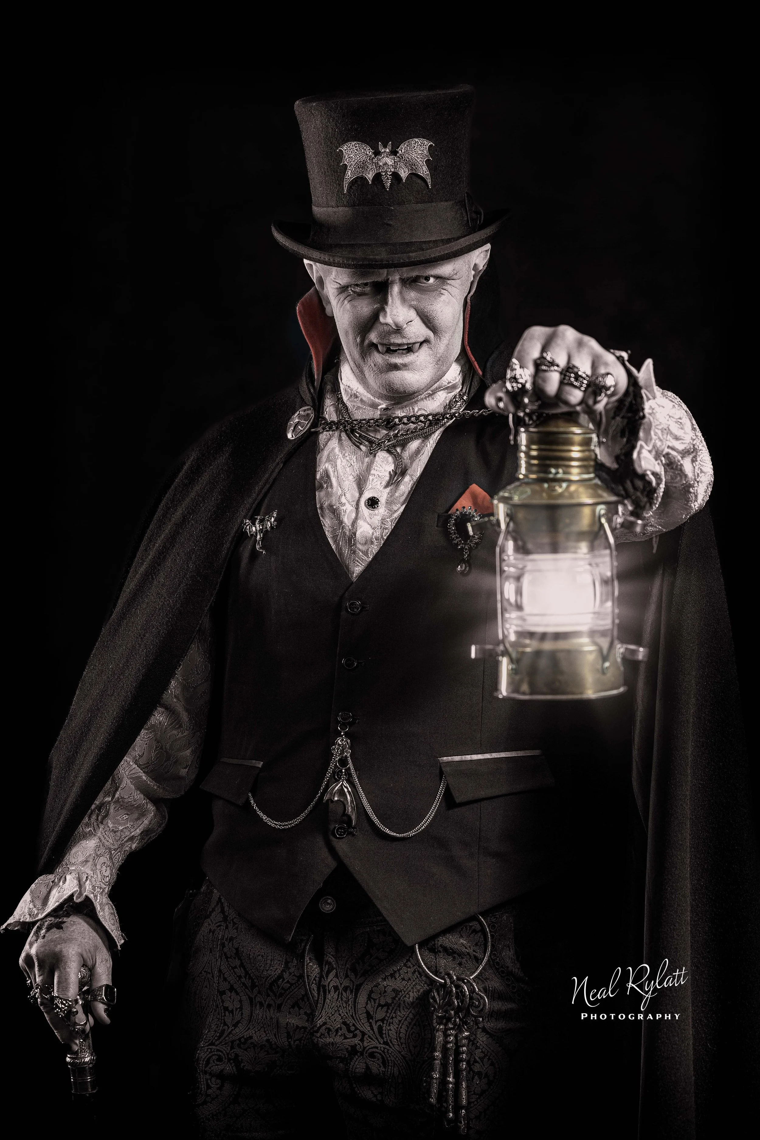 Gothic steampunk man in a top hat holding a lantern against a dark background