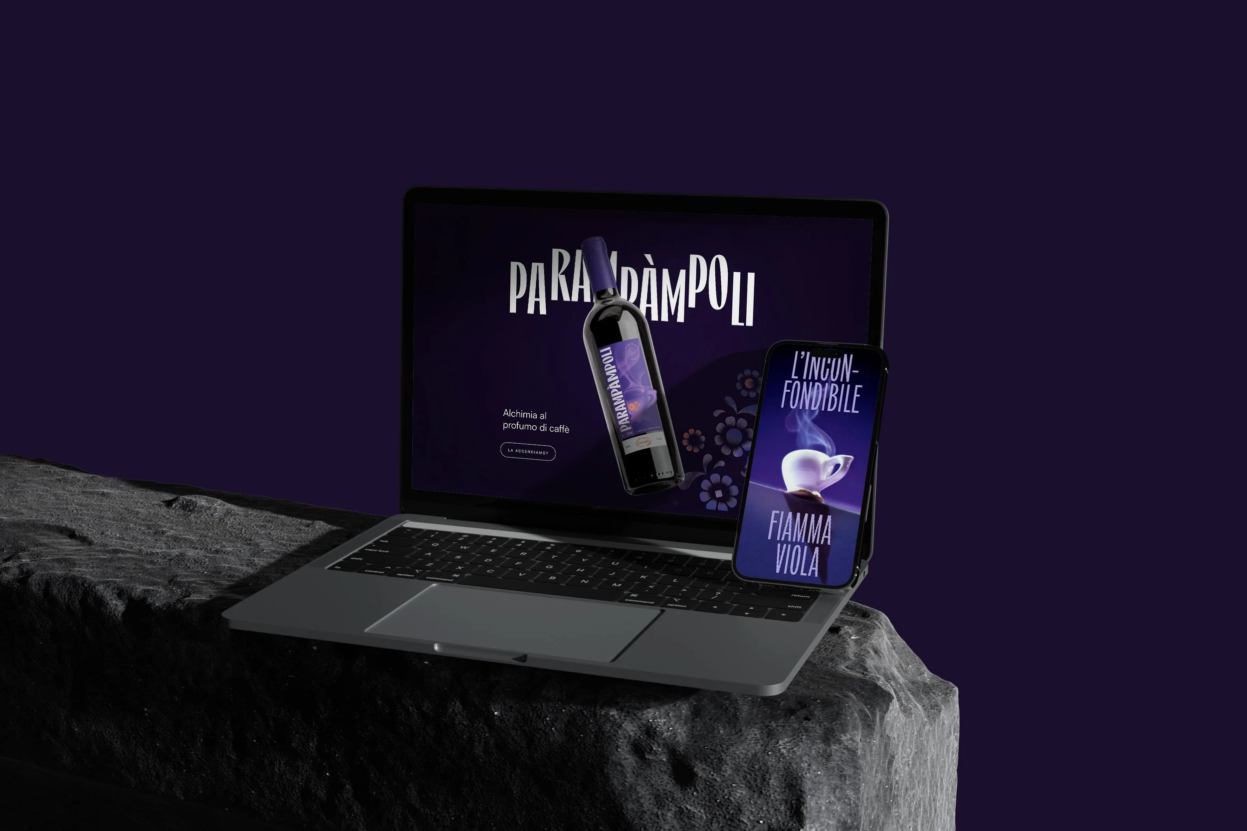 Immagine di un computer portatile che mostra uno schermo una bottiglia di vino con etichetta viola, accompagnato da uno smartphone con schermo che recita "L'INCONFONDIBILE" e "FIAMMA VIOLA". La scena si svolge su una superficie di pietra con sfondo di colore viola scuro.