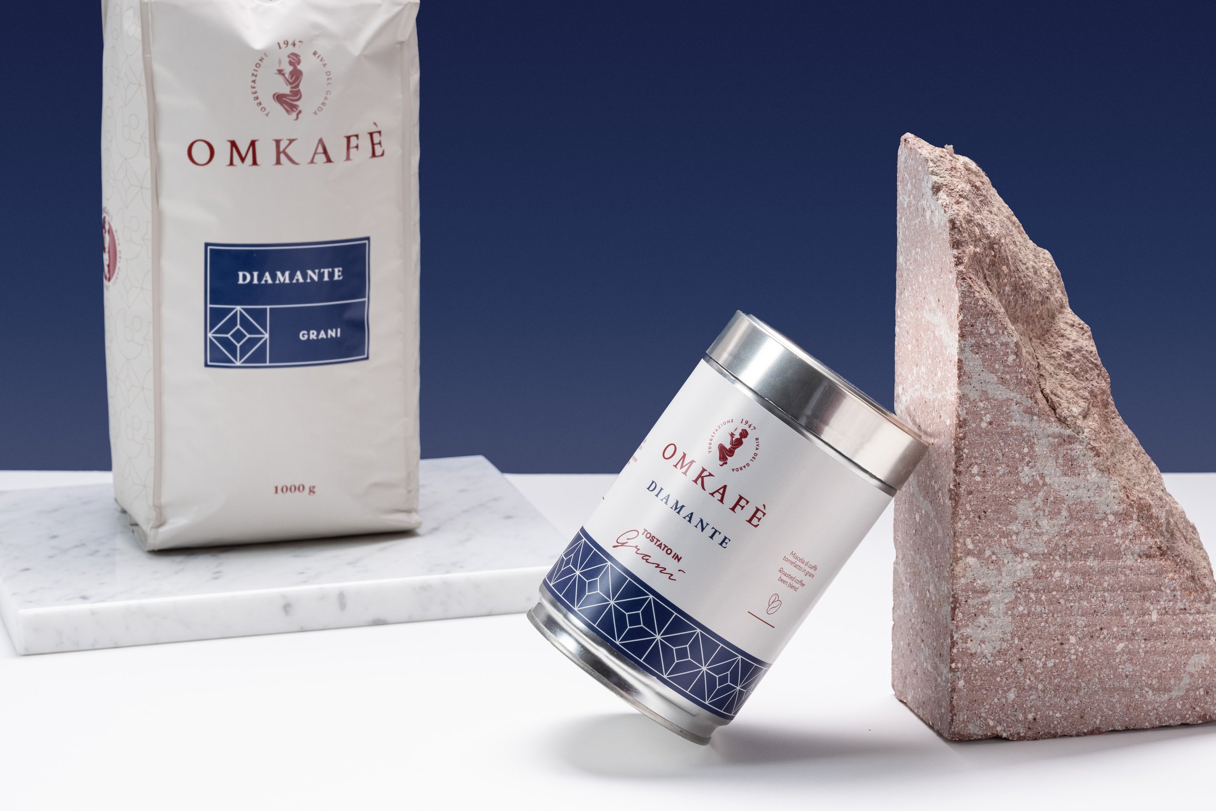 barattolino di caffe con etichetta DIAMANTE `appoggiato ad una superficie a specchio e mostra il pattern blu con geometrie a forma di diamante
