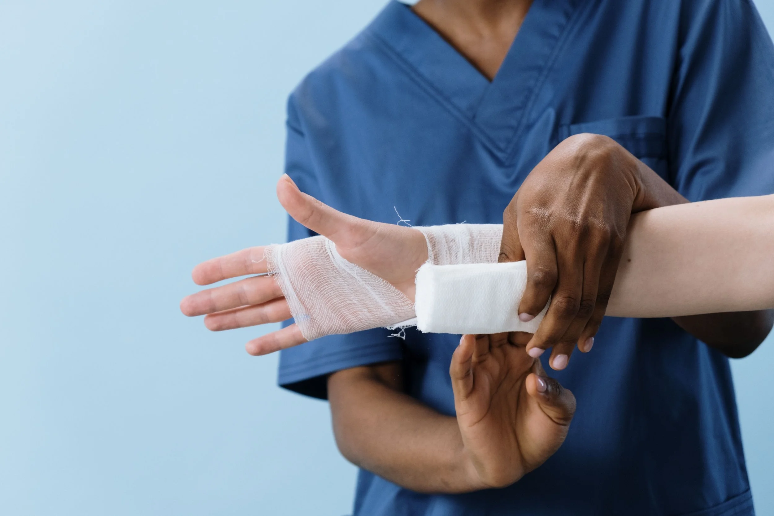 A healthcare professional is helping someone with a bandaged finger, demonstrating care and assistance.
