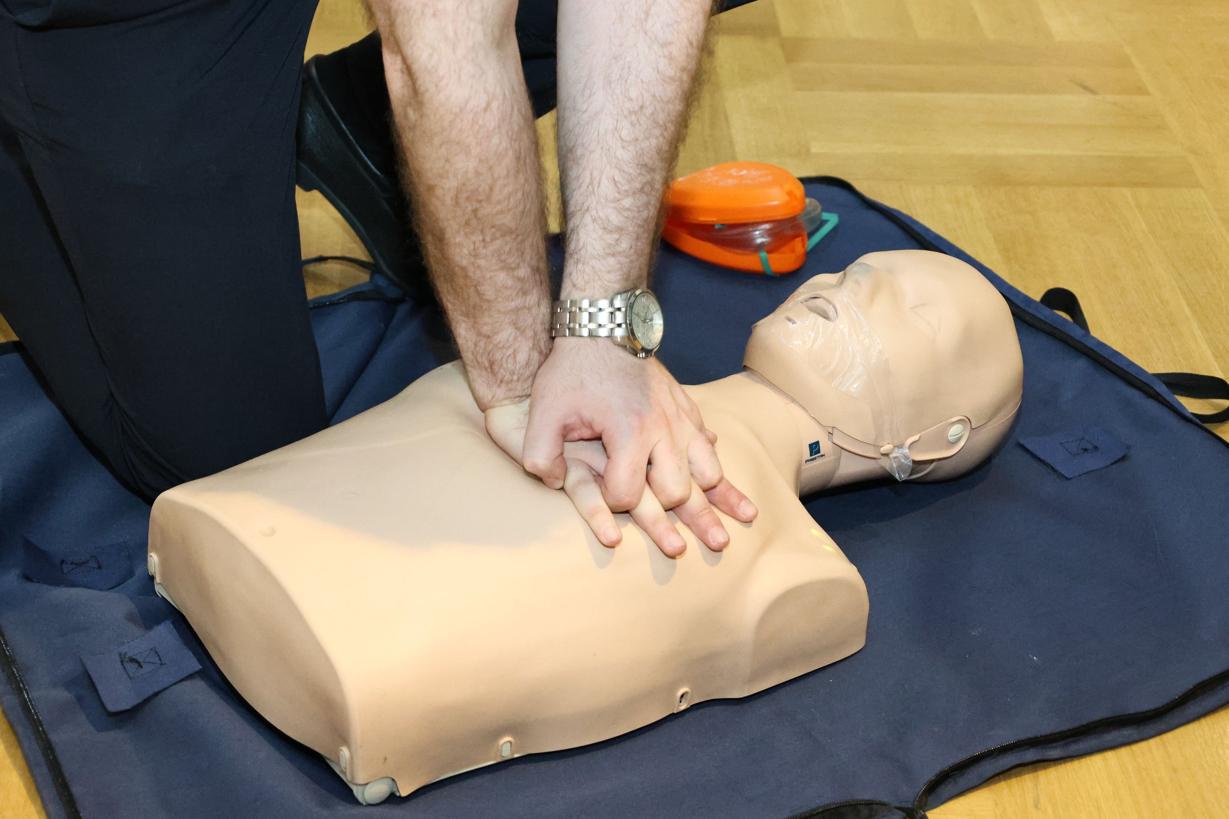 Person performing CPR on a training mannequin during a CPR training session.