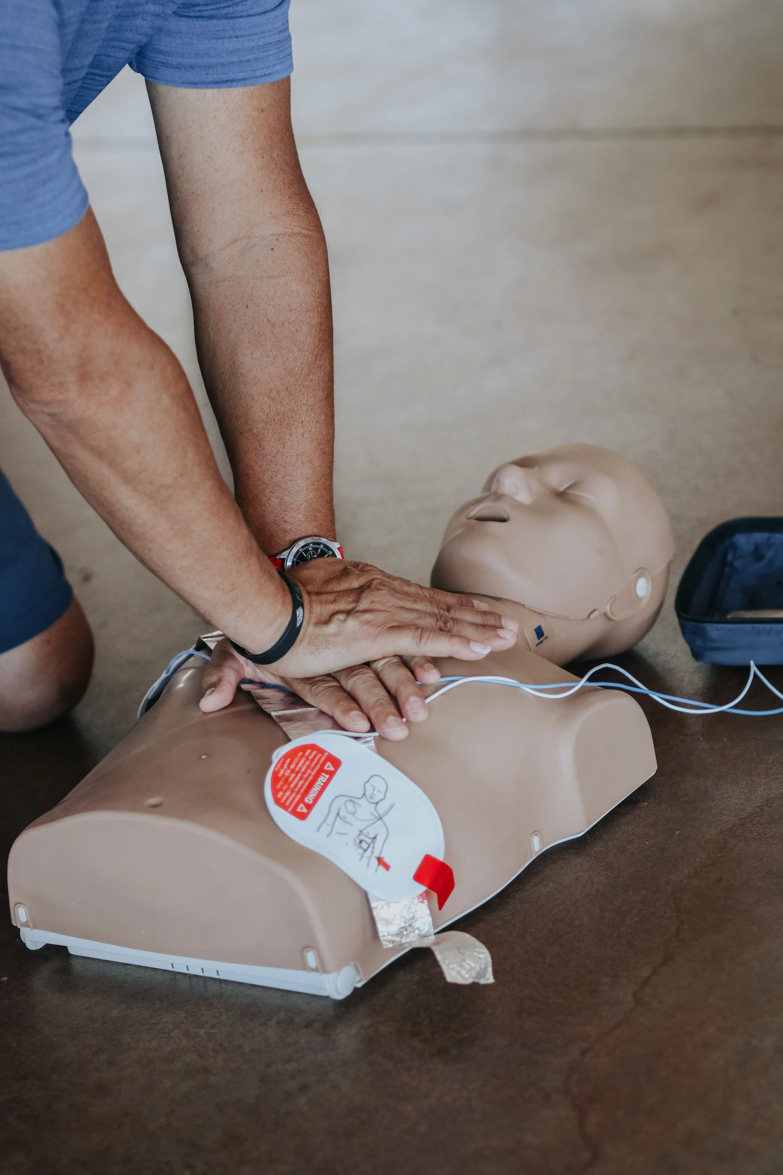 A person practicing CPR on a medical training mannequin, demonstrating chest compressions.