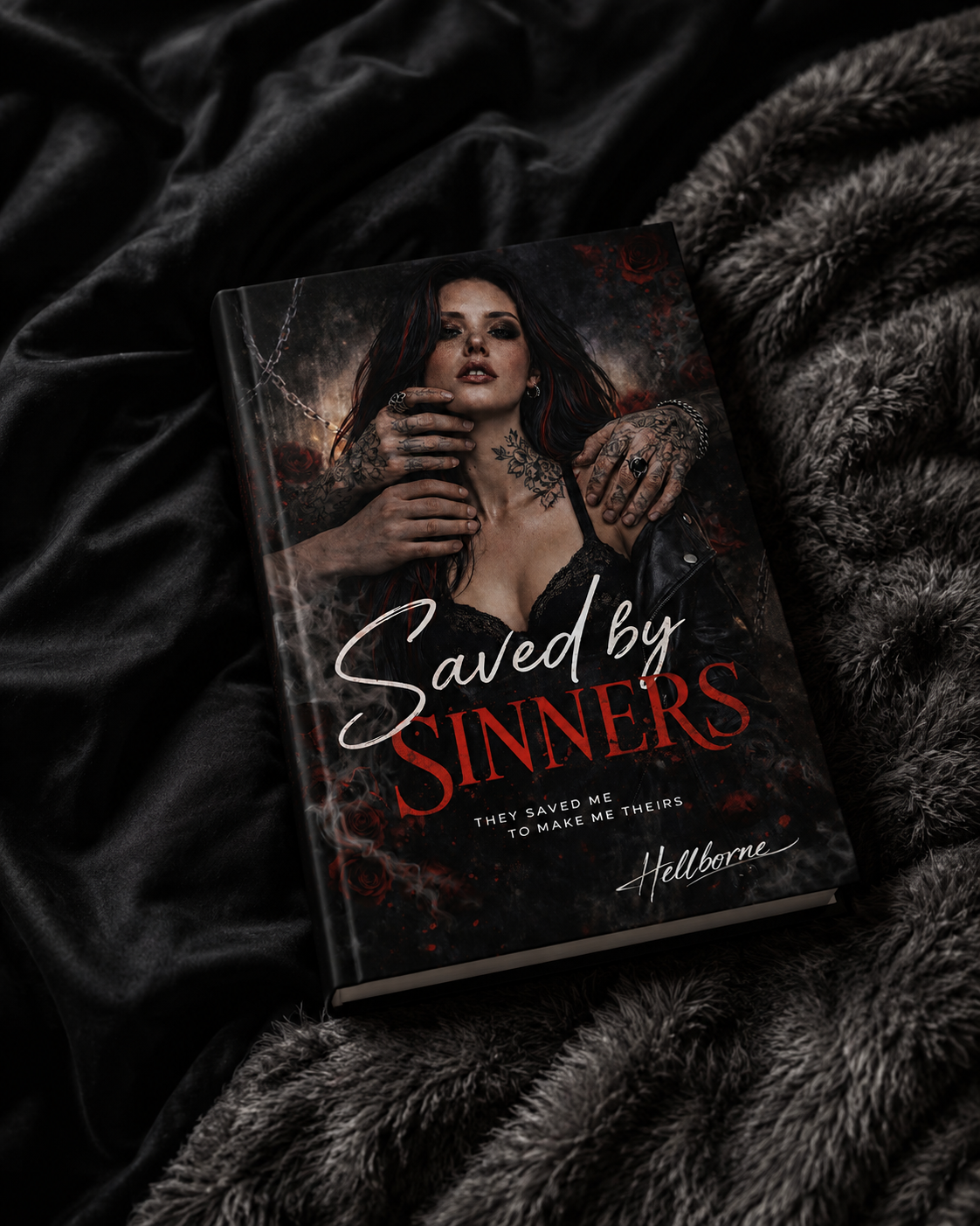 Book titled "Saved by Sinners" with a dark, gothic cover featuring a woman with tattoos and dark makeup, resting on black velvet and fur blankets.