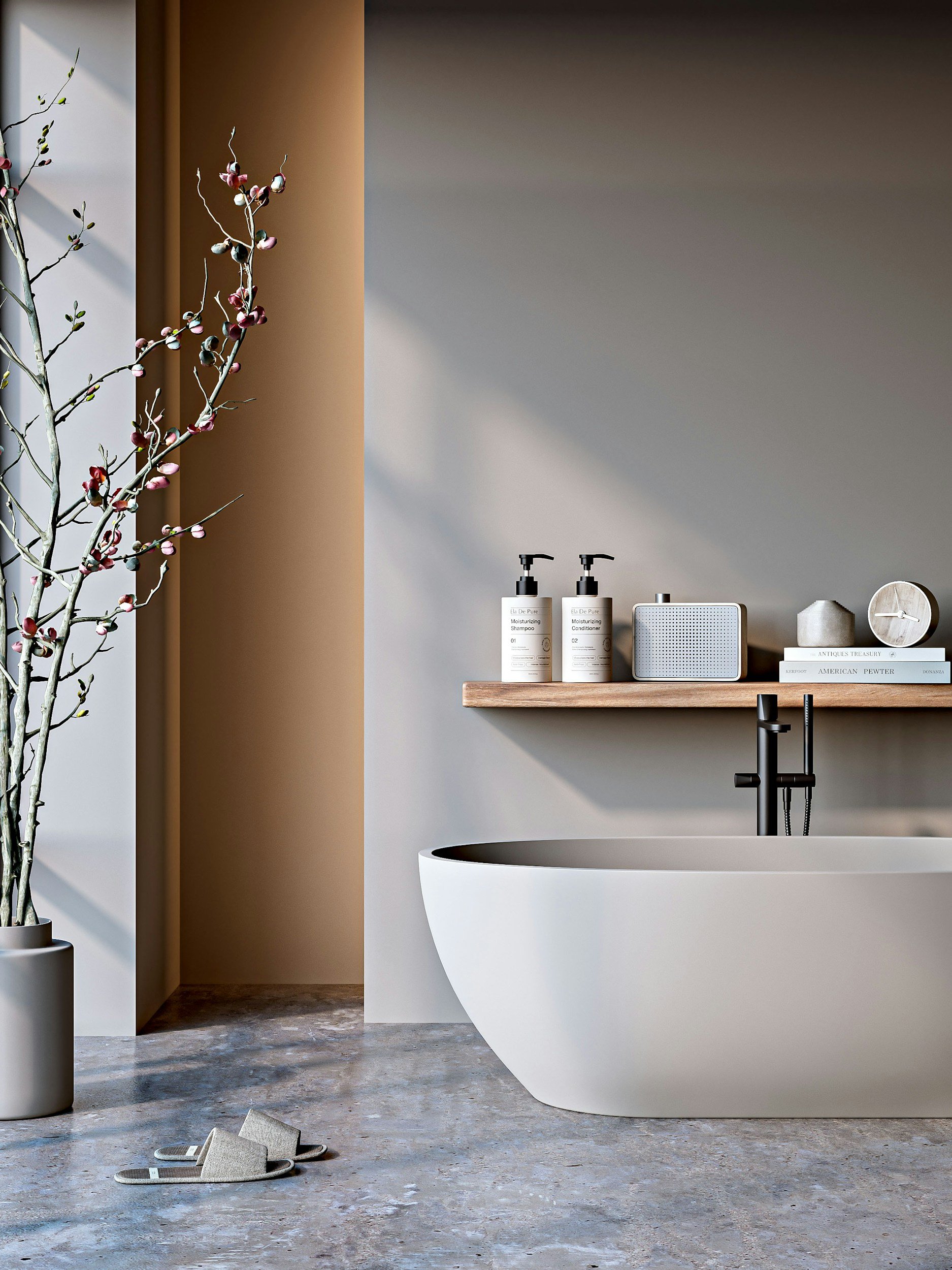 Modern bathroom with a freestanding bathtub, two black pump soap dispensers, a speaker, a small sculpture, and a stack of books on a wooden shelf. A tall vase with a branch and pink blossoms stands to the left, and a pair of beige slippers are on the floor.