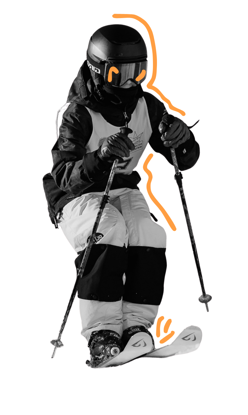 A skier dressed in snowboarding gear, including a helmet and goggles, is in a crouched position with ski poles and skis, on snow, as if ready to make a turn.