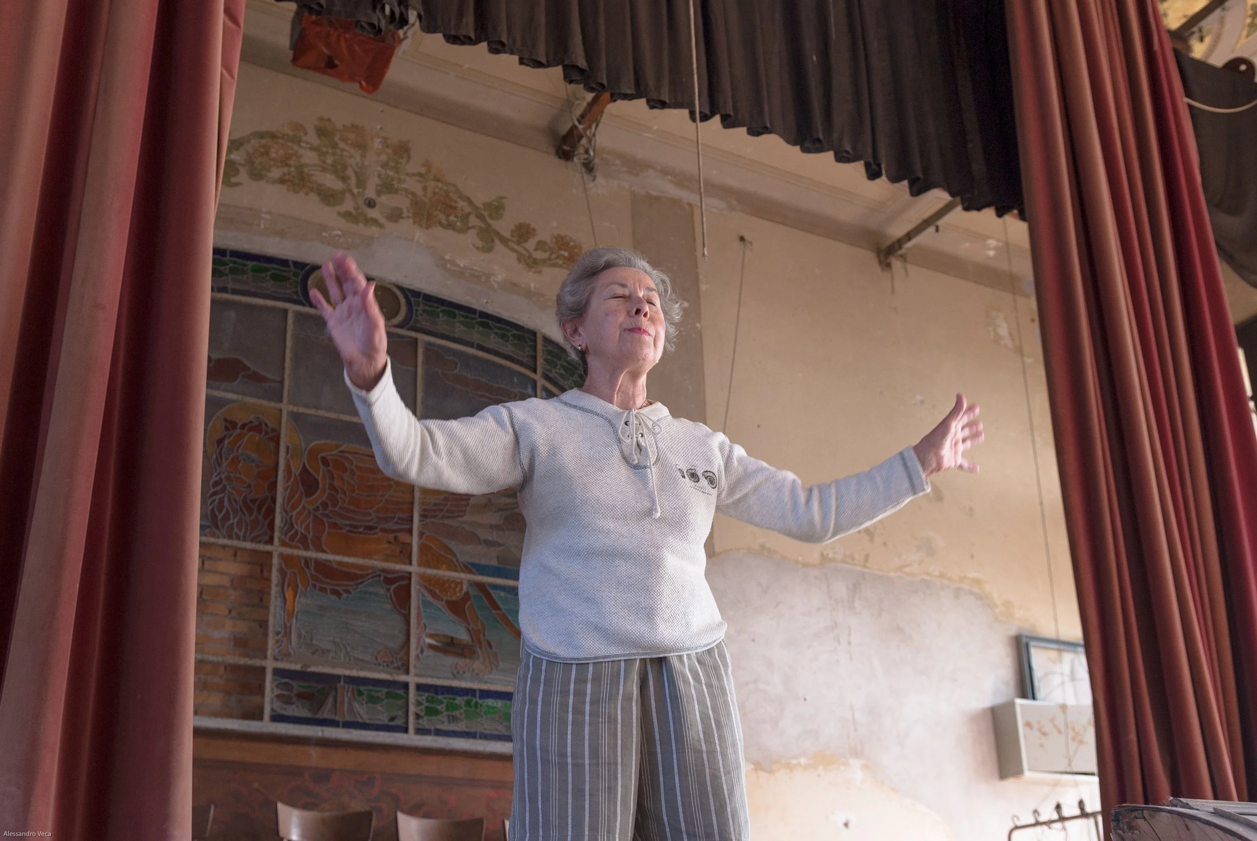 Donna con le braccia aperte sul palco del Teatro Marinoni durante un momento di partecipazione culturale