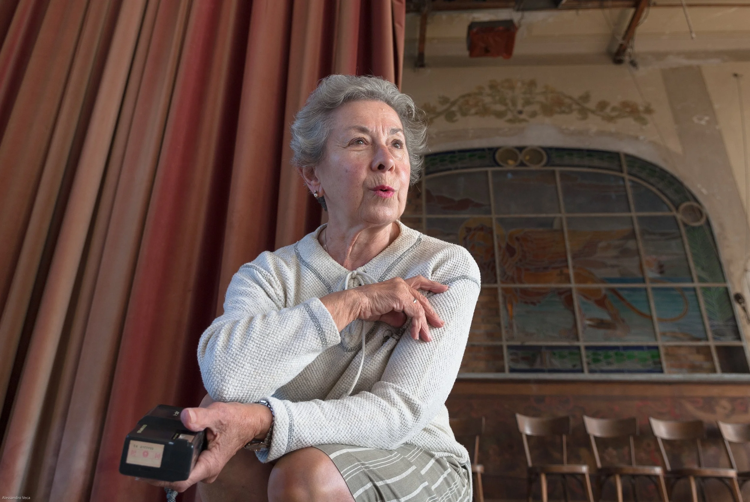 Ritratto di una donna all’interno del Teatro Marinoni tra sipario, palco e decorazioni storiche