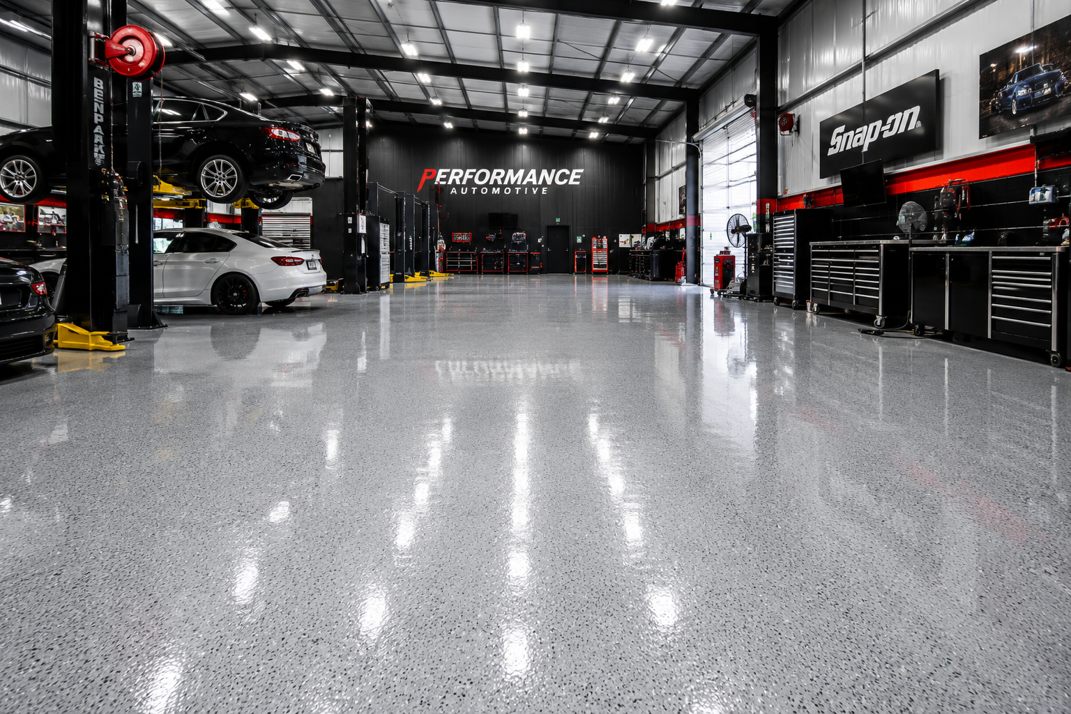 Interior of an automotive repair shop with cars on lifts, tool cabinets, and performance equipment