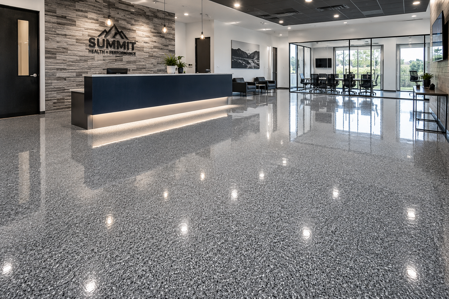 Modern lobby with polished terrazzo floor, reception desk, black chairs, large windows with views outside, and a wall mounted flat screen TV.