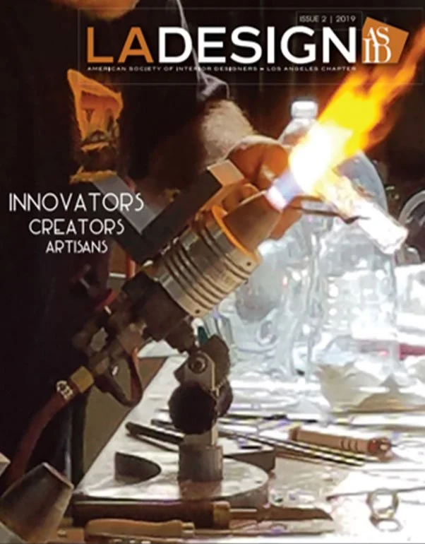 A person working with a blowtorch creating fire on a piece of metal in a workshop. The table has various tools, and the background shows workshop equipment.