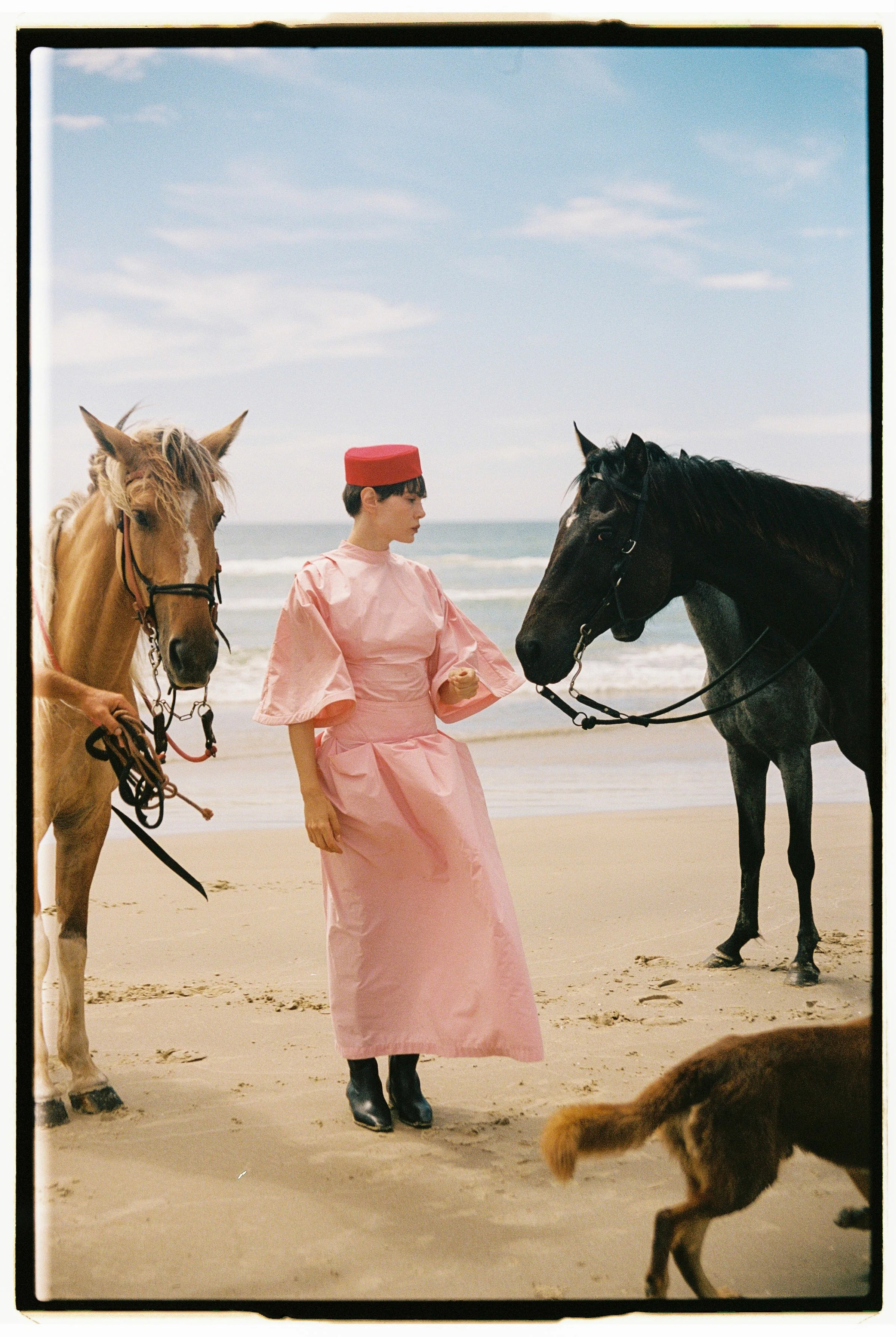 Model wearing Mayara Junges between two horses on a beach in Brazil