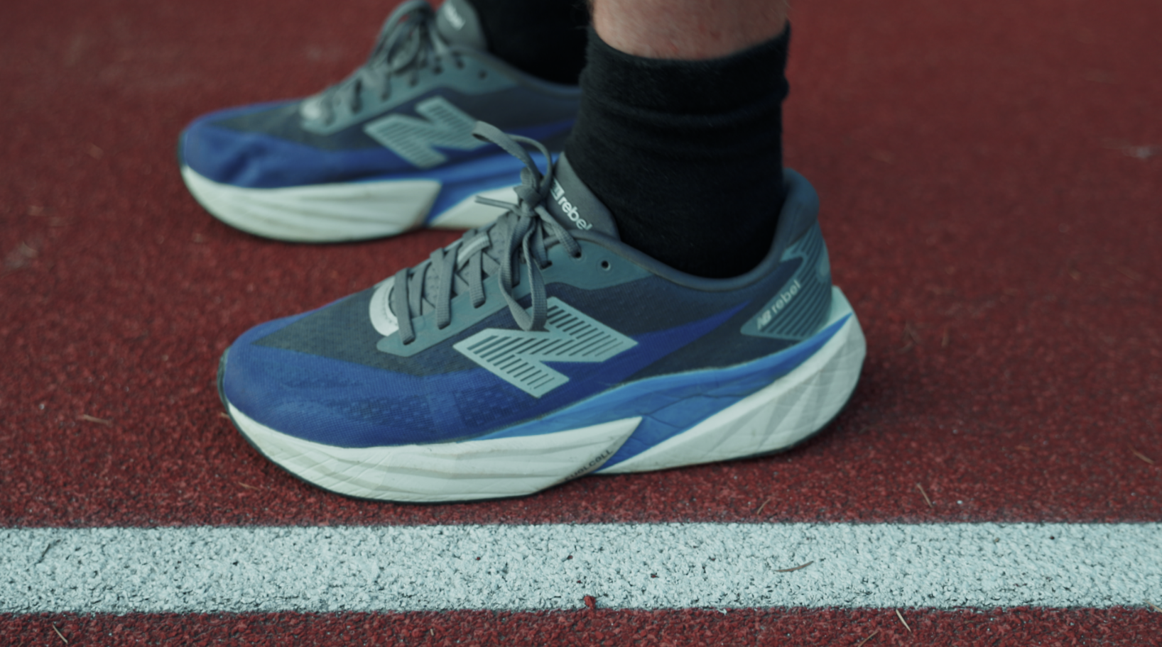 Une paire de chaussures de course de couleur bleue sur une piste en tartan rouge.