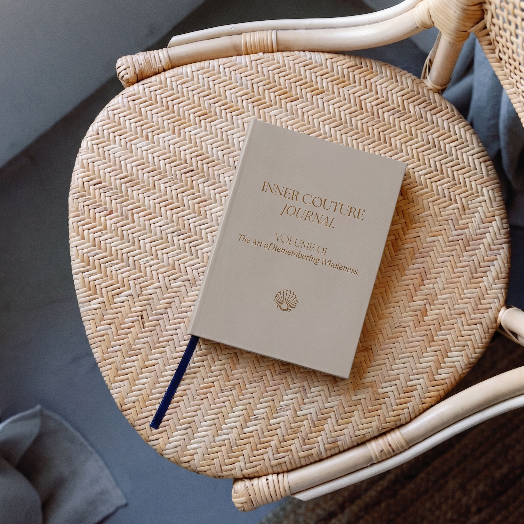 Ein Buch mit dem Titel »Inner Couture Journal«, das auf einem geflochtenen Stuhl liegt.