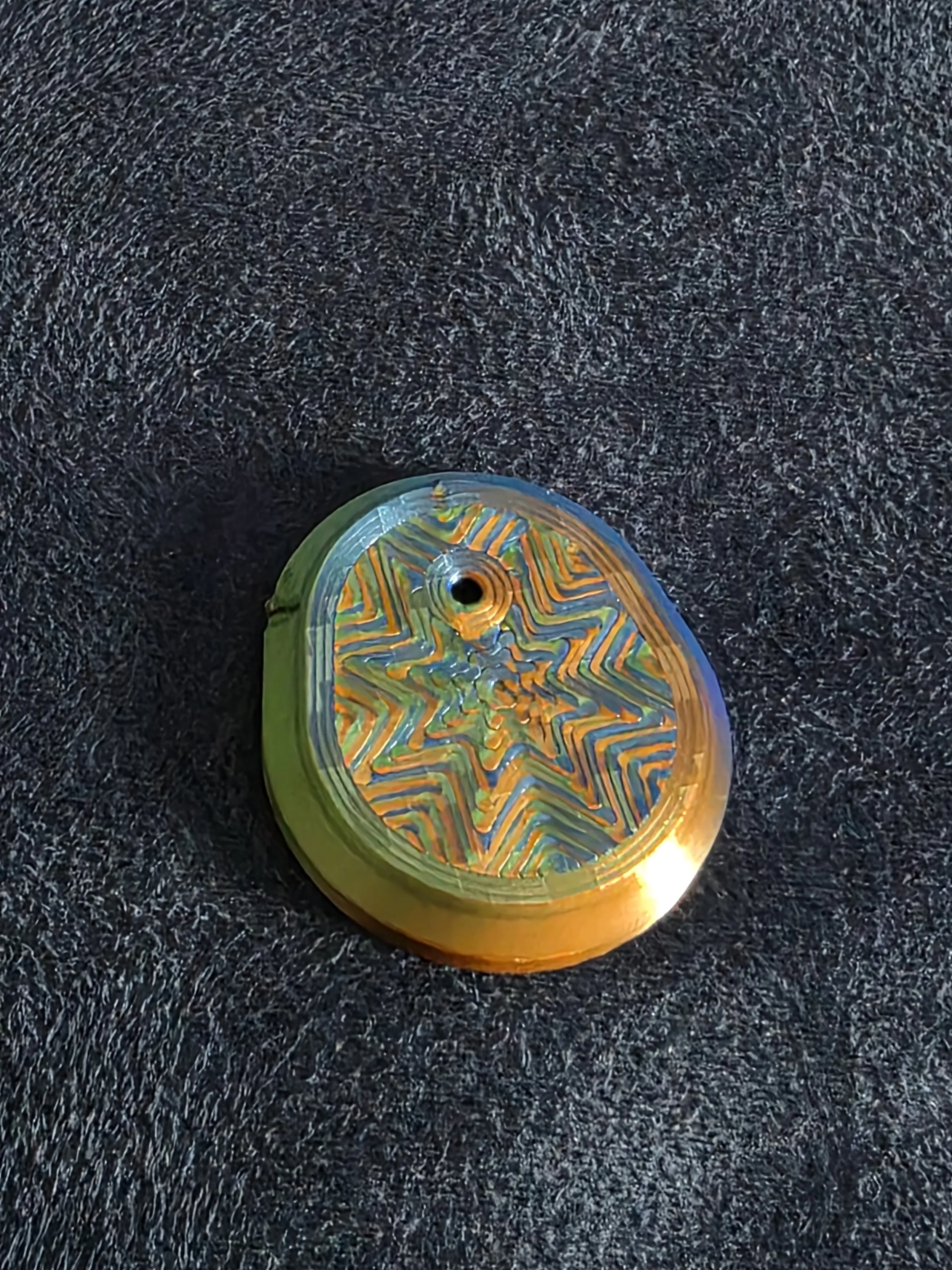 Colorful skateboard wheel with orange, blue, and yellow patterns on a black textured surface.