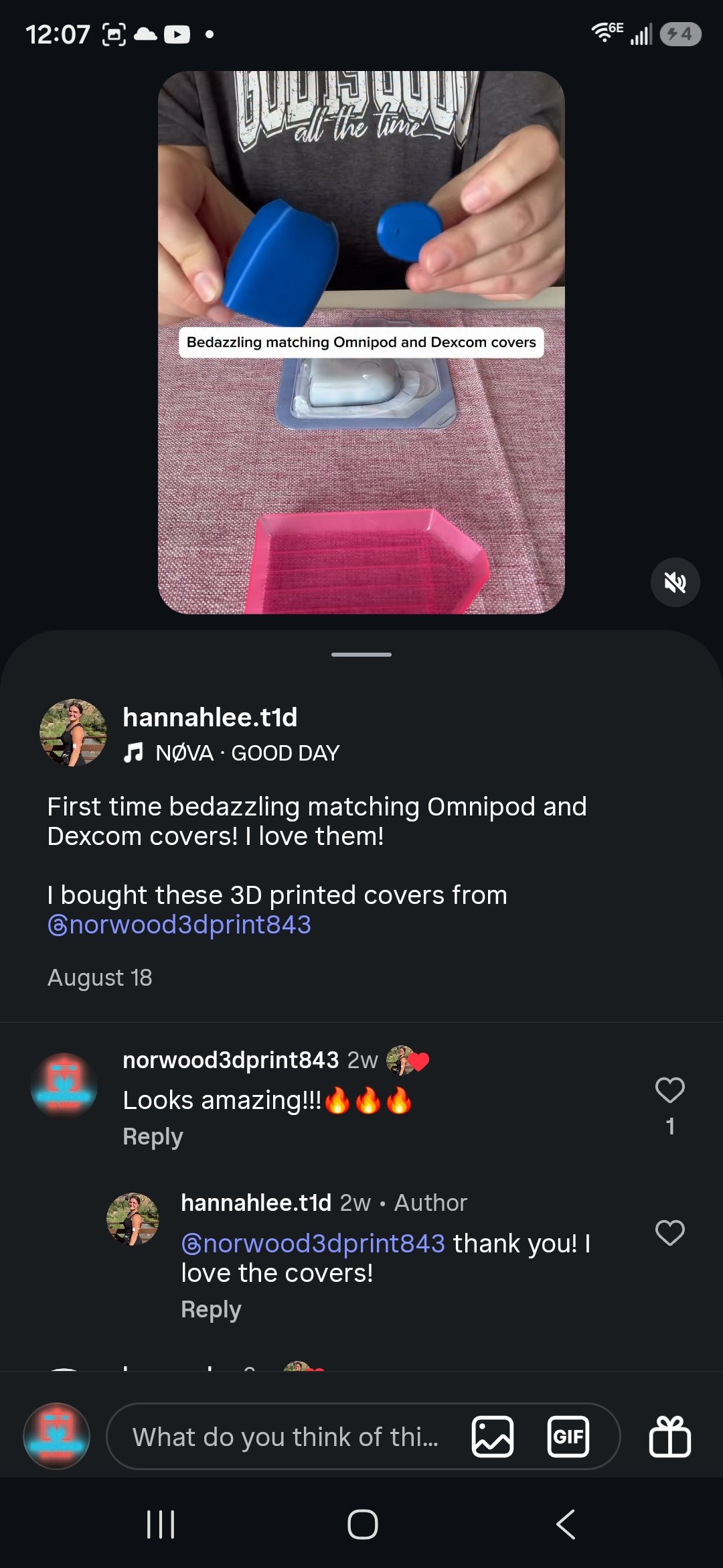 Person holding two blue 3D-printed covers over a tabletop, with a pink container and a plastic-wrapped electronic component nearby.