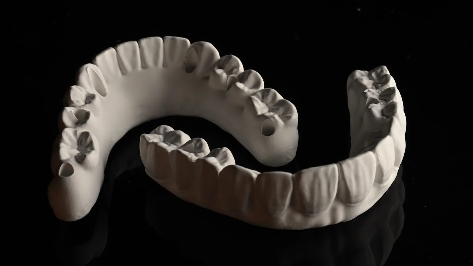 A white dental model of the upper and lower teeth displays on a black background.