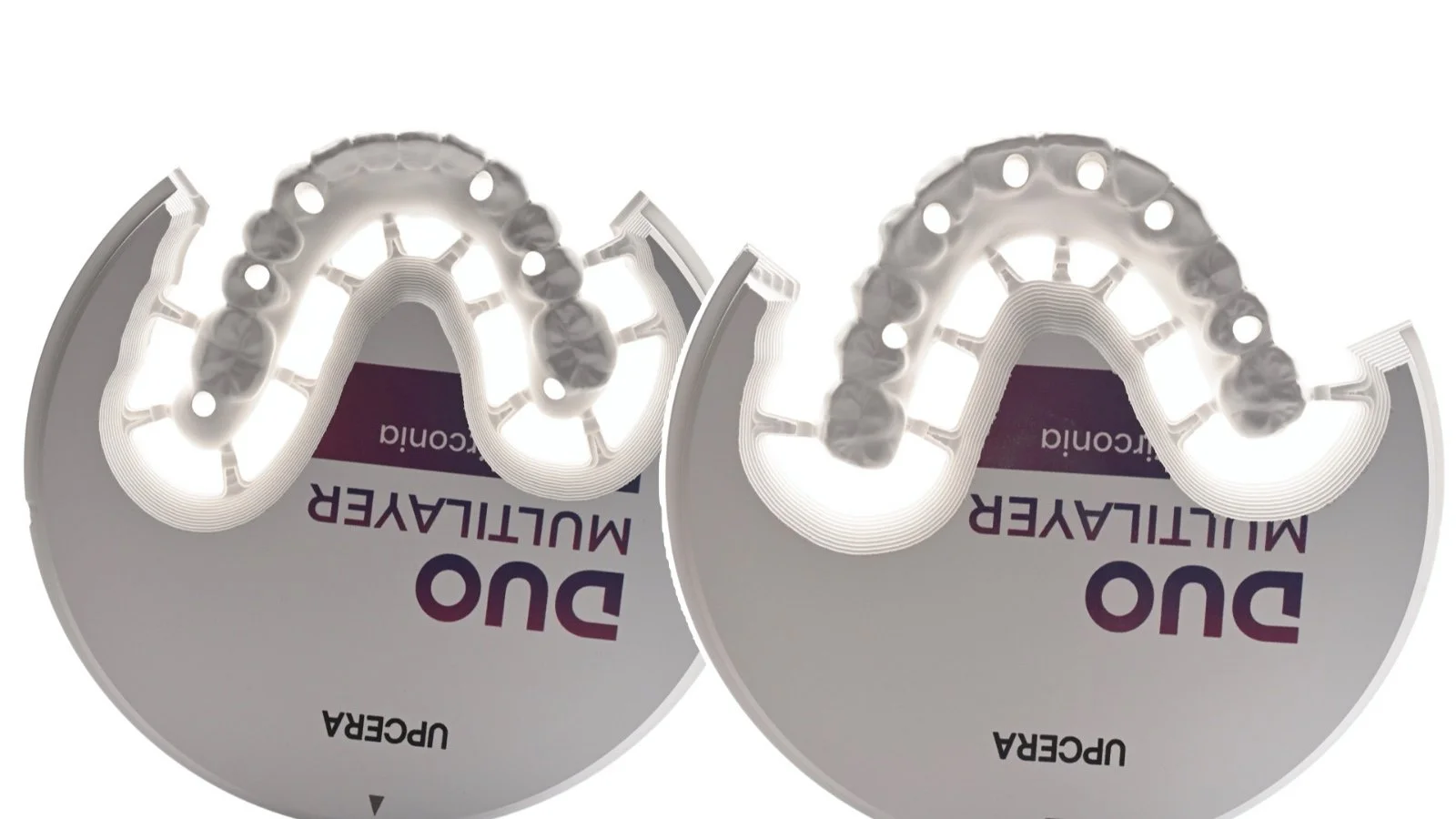 Upside-down image of two circular dental teeth whitening trays with LED lights and a purple package with the brand "DUO" and the words "Multi-Layer Whitening" on it.