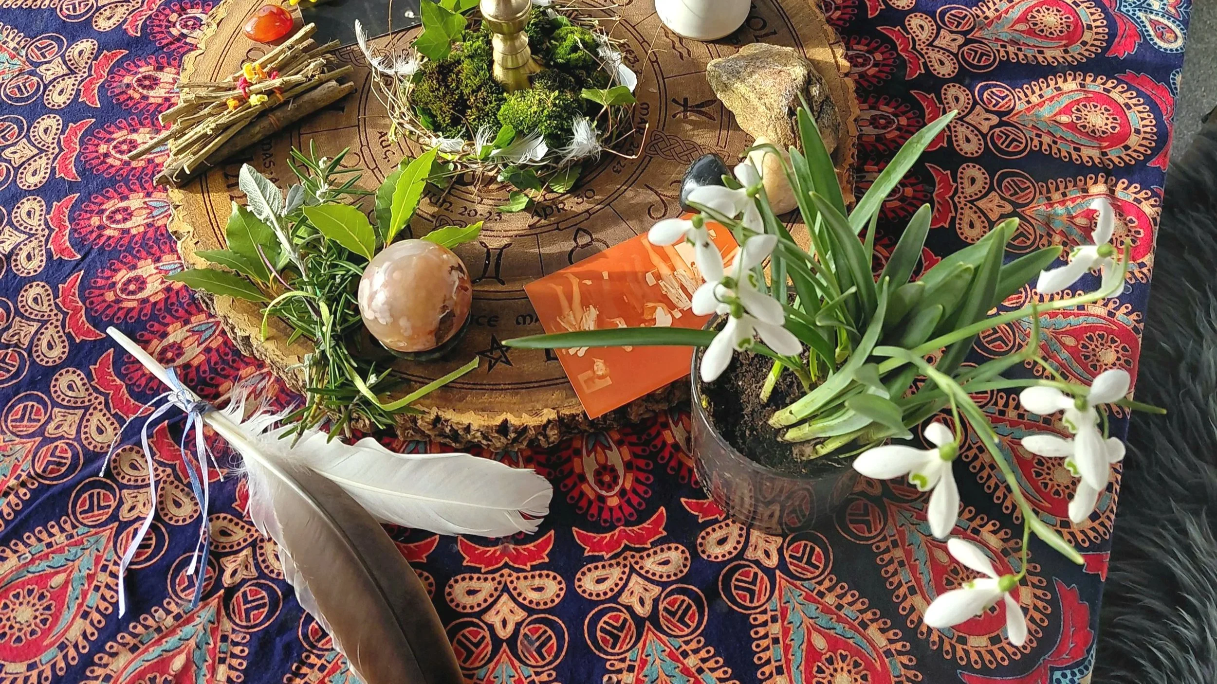 Detail of a ceremonial altar featuring snowdrops and feathers